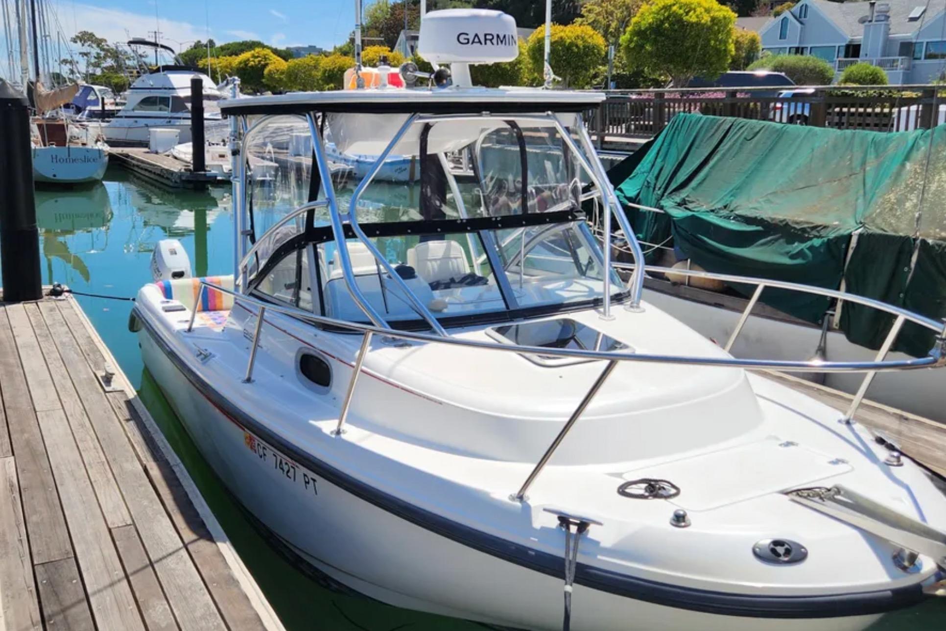 2000 Boston Whaler 21 Conquest boat docked in a marina with clear water.