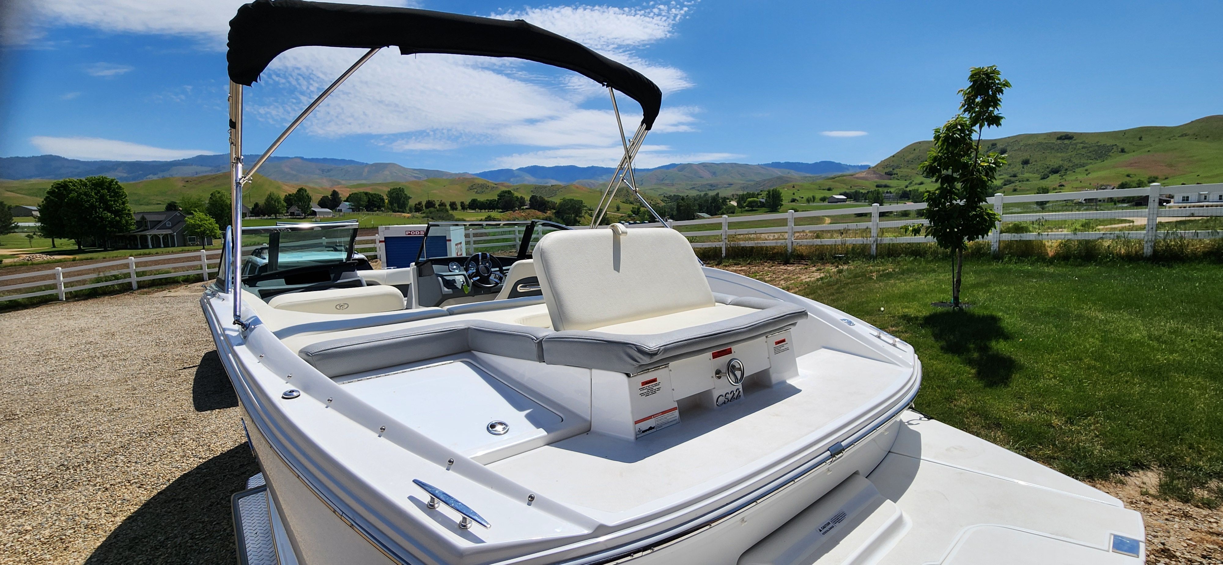 A white Cobalt CS22 boat is on a trailer in a rural setting.