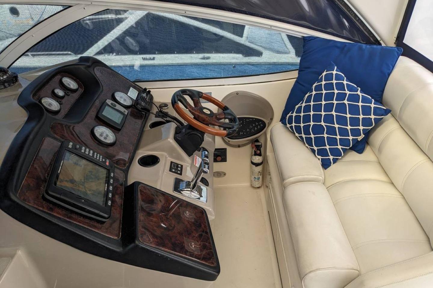 Helm of 2003 Cruisers 3970 yacht with navigation instruments and cushioned seating.