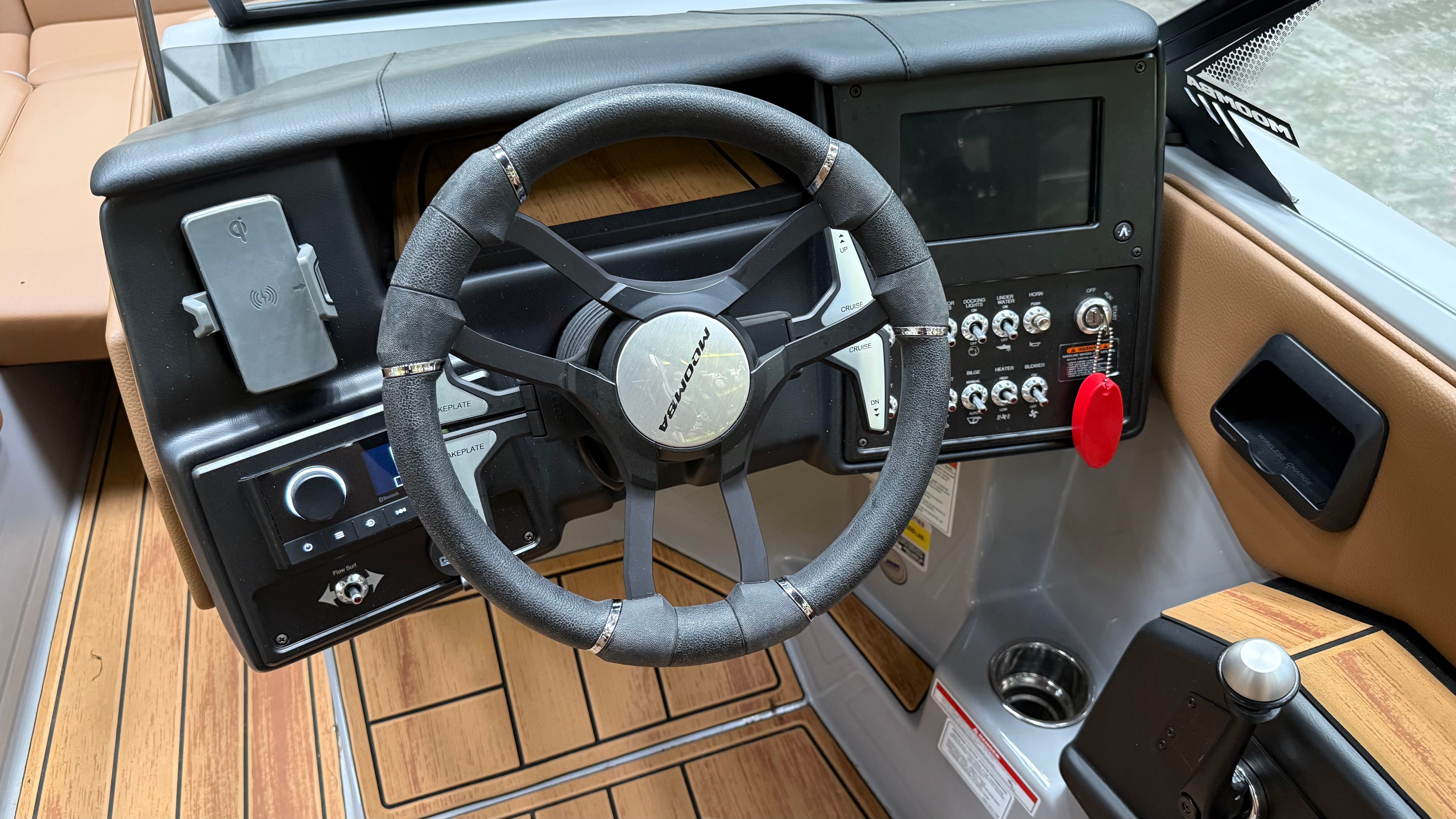 The image shows the cockpit of a Malibu Mojo boat with a modern steering wheel and dashboard.