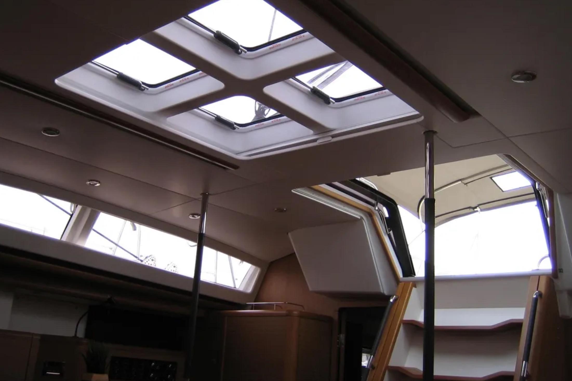 Interior view of 2011 Jeanneau 57 yacht, featuring skylights and wooden stairs.