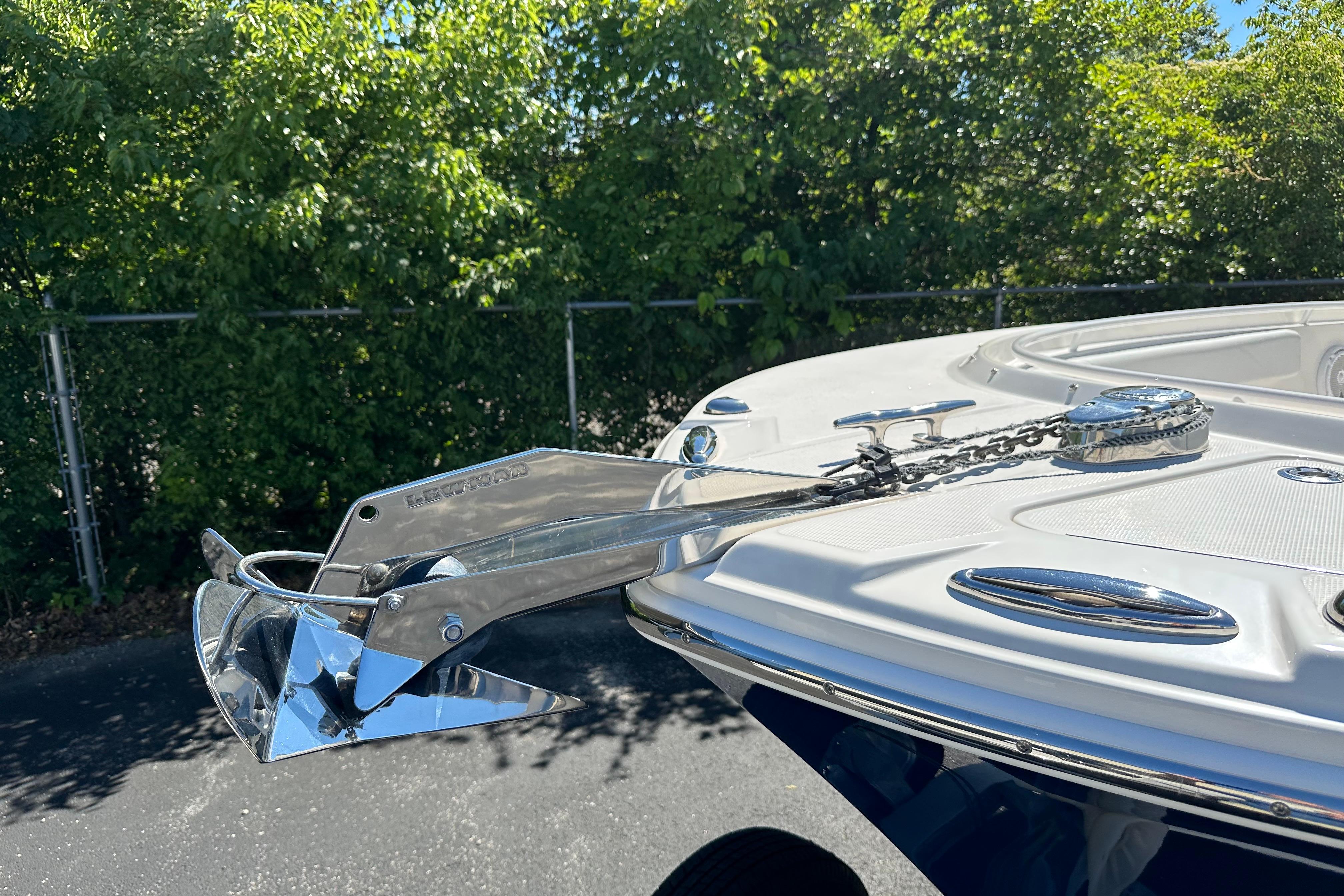 Bow of 2015 Edgewater 245CC boat with anchor and chain, surrounded by greenery.