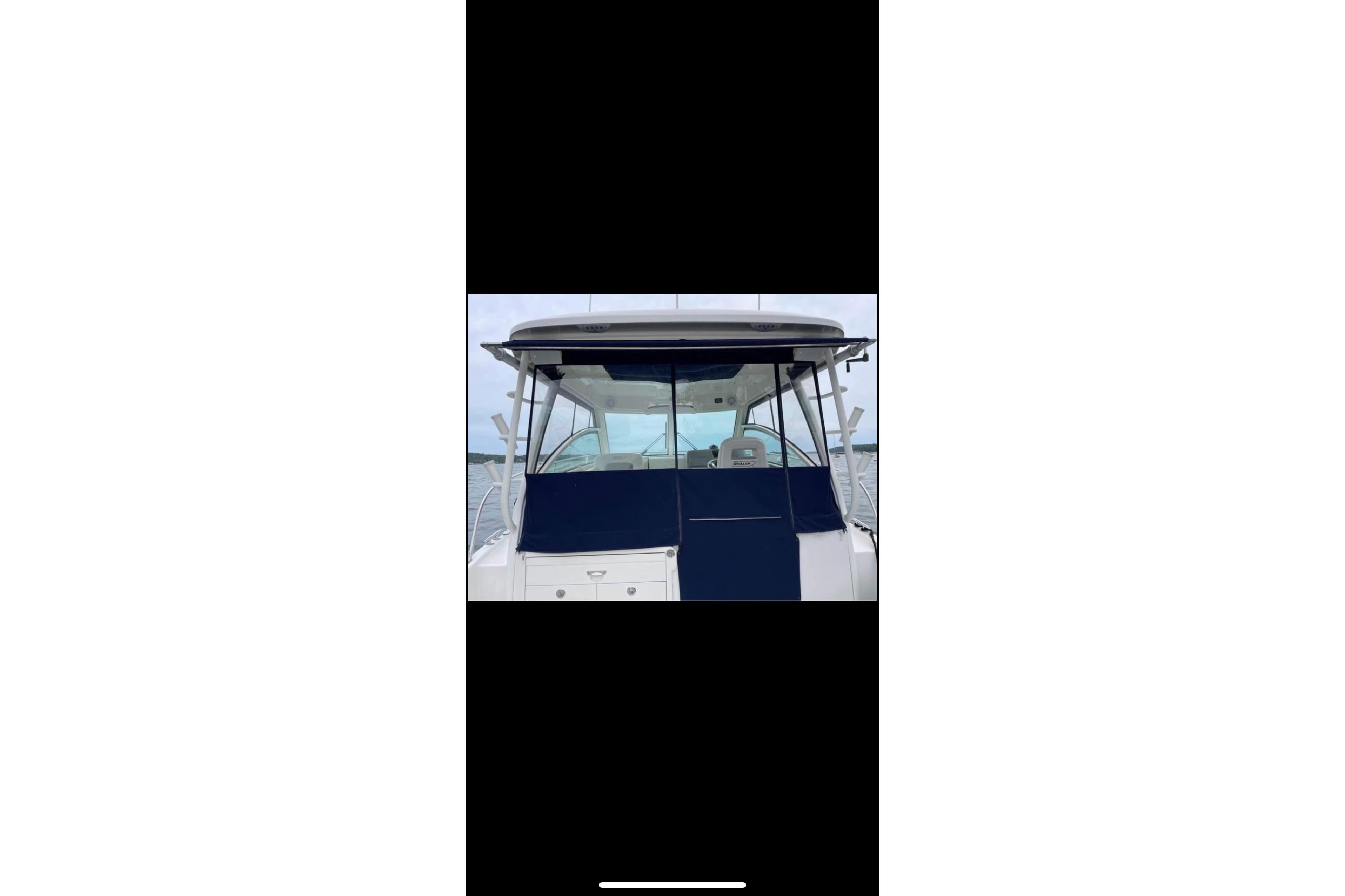 2013 Boston Whaler 315 Conquest boat with blue cover on water.