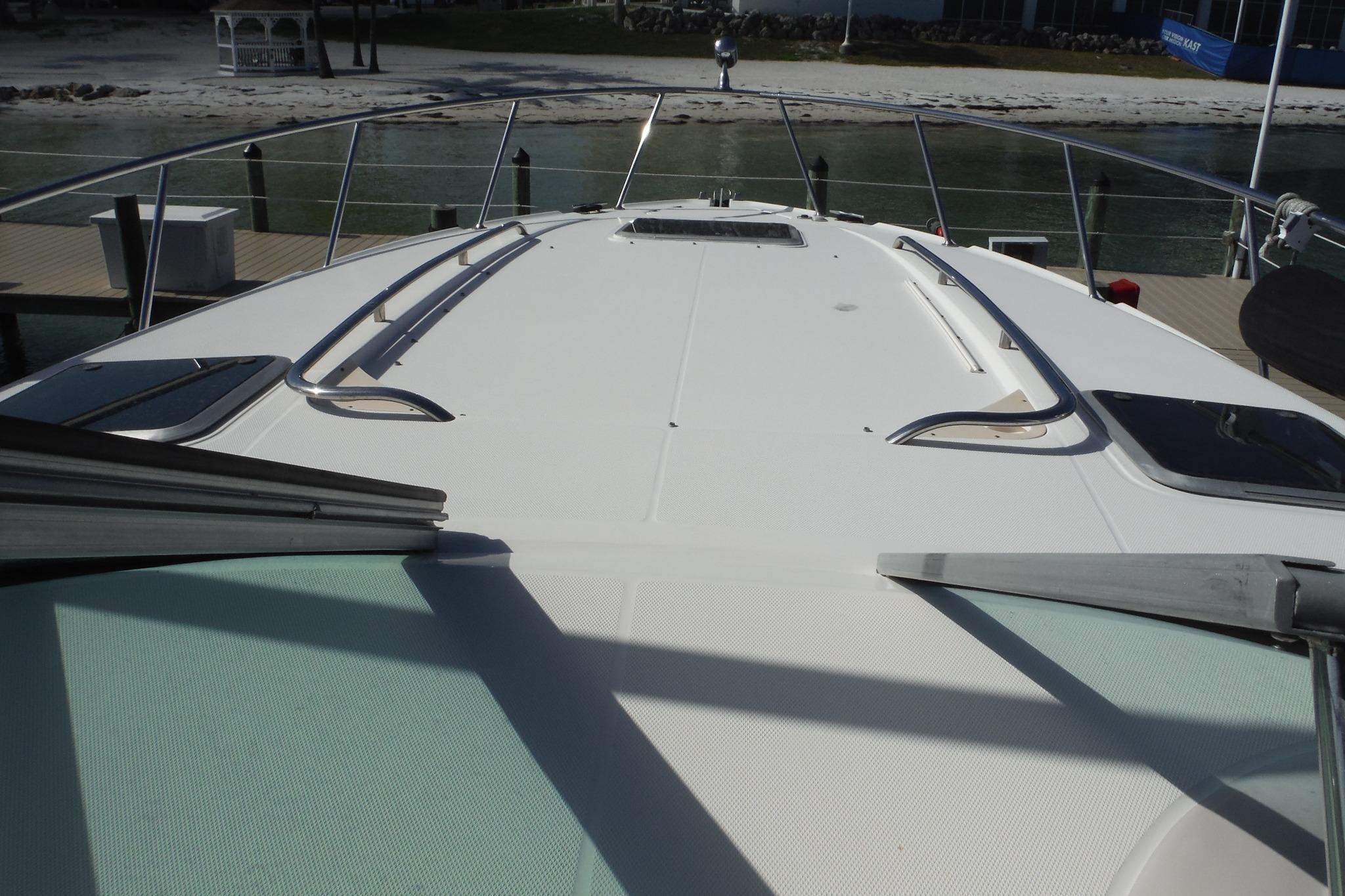 2005 Chaparral Signature 350 yacht deck with railing, docked by a sandy shore.