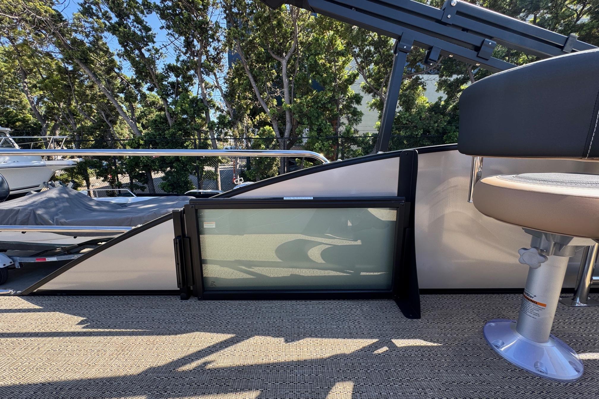 2026 Barletta Cabrio 24UE pontoon boat interior with seating and railing, surrounded by trees.