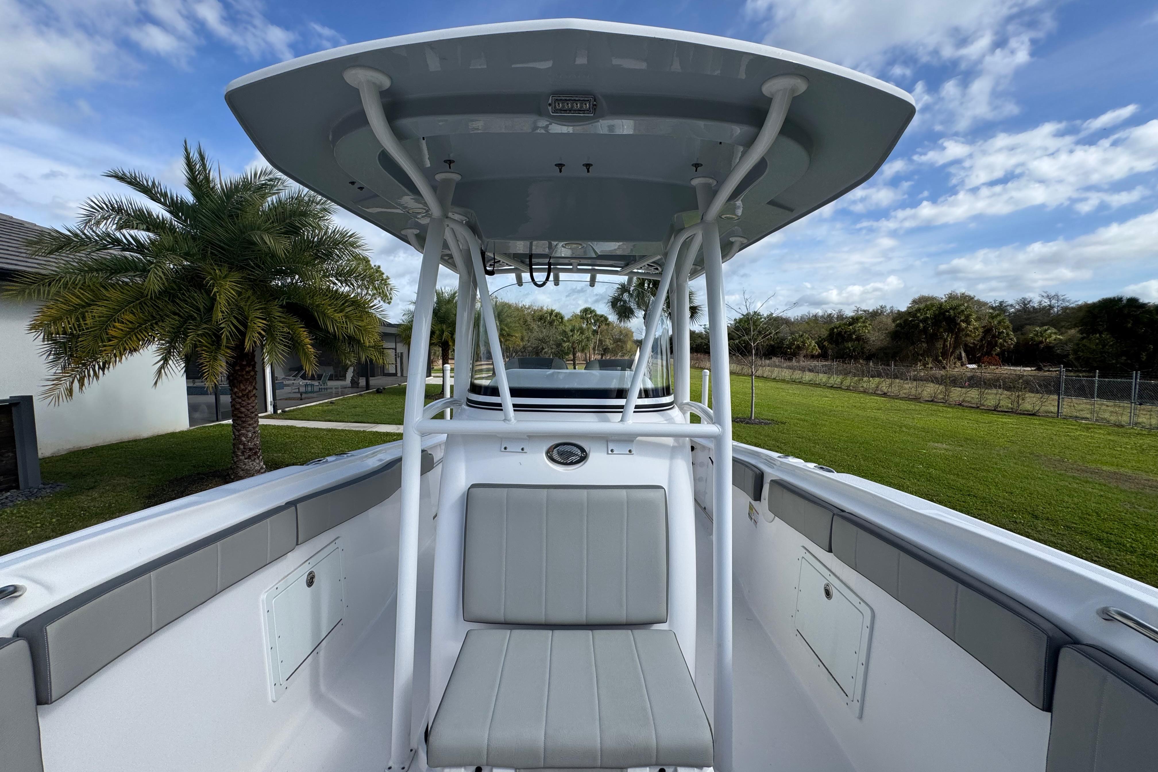 2022 Aquasport 2500 Center Console boat with T-top, parked near palm trees.