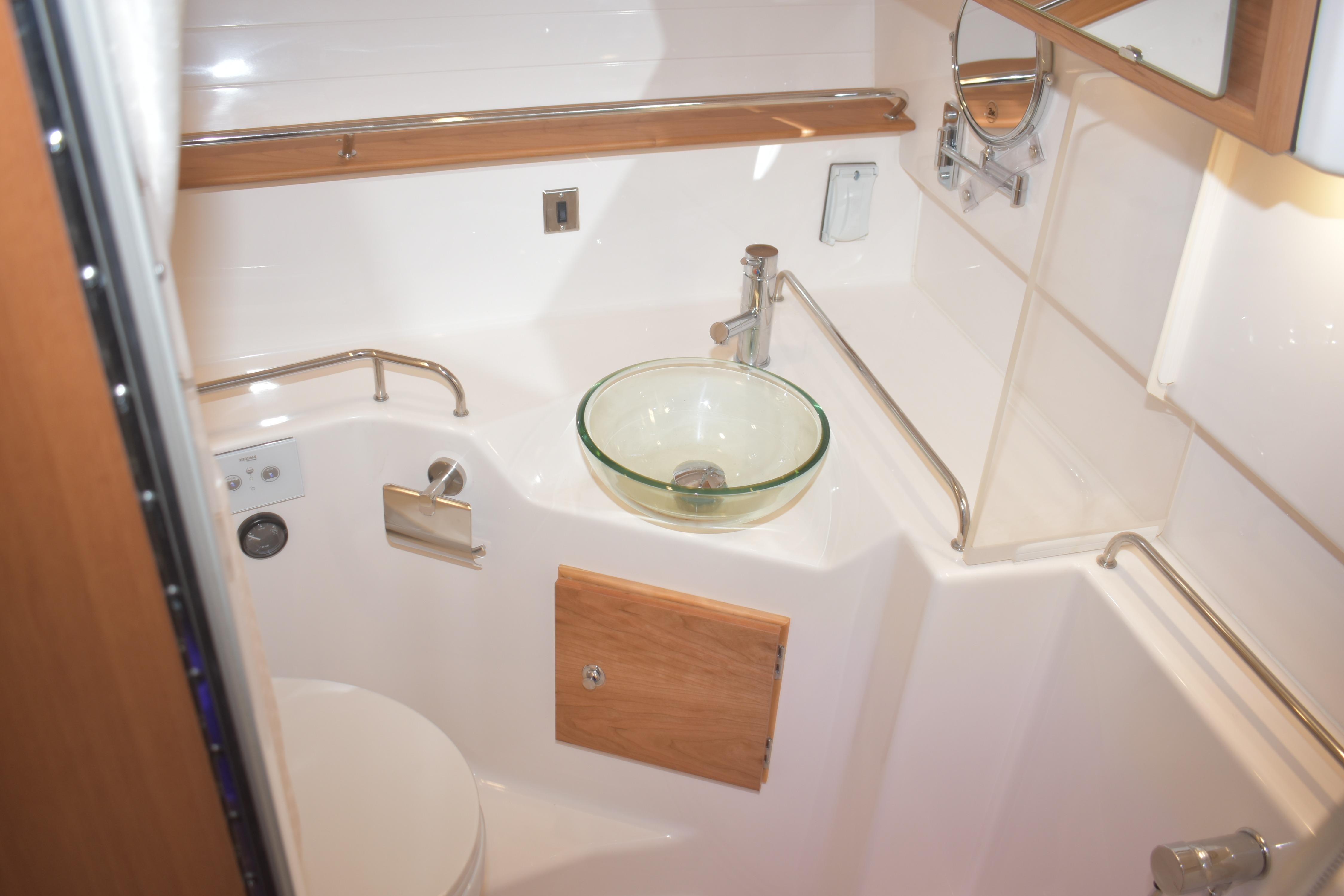 Compact bathroom in 2026 Cutwater C-32 CB boat with glass sink and modern fixtures.