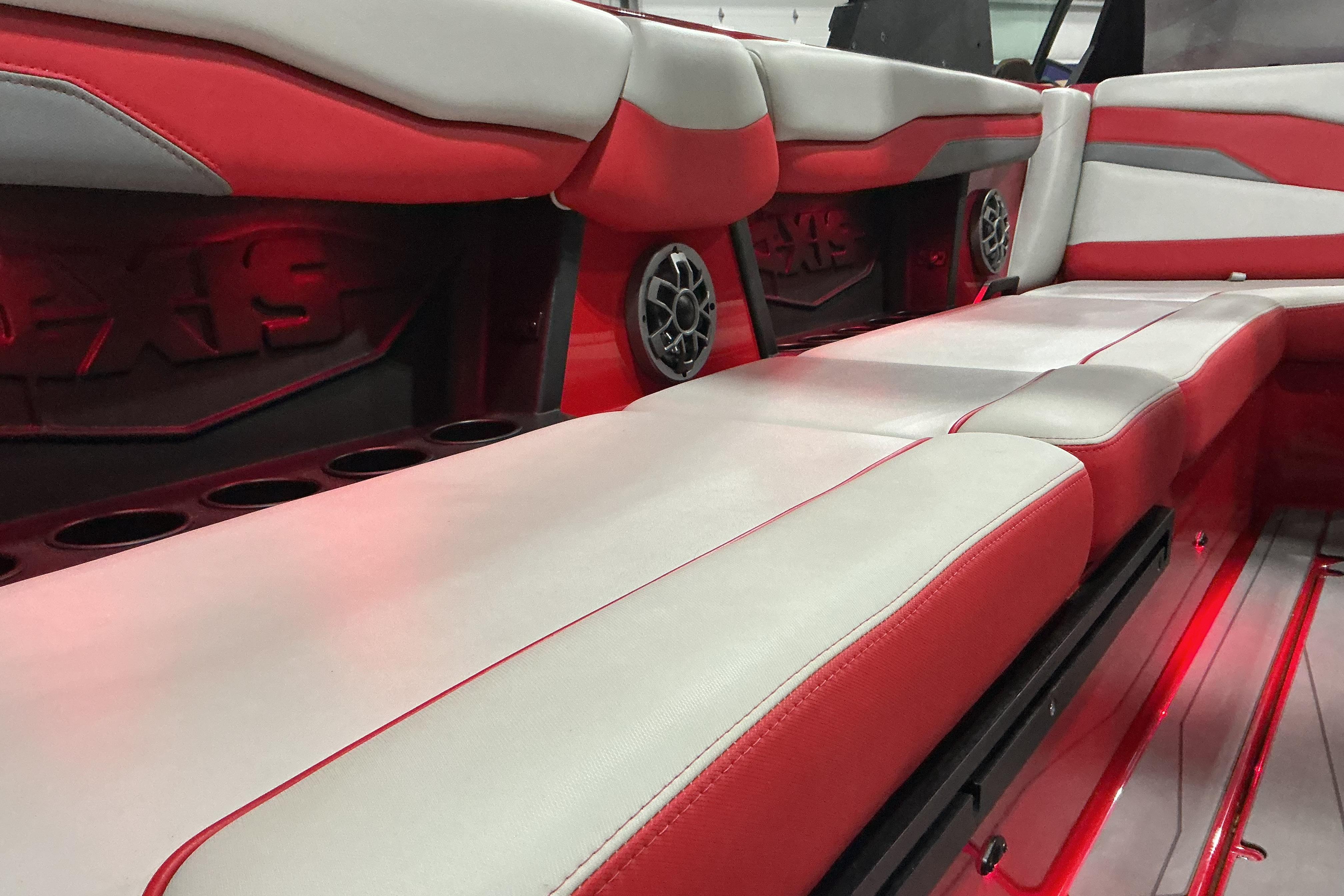 Red and white interior of 2022 Axis T250 boat with speakers and cup holders.