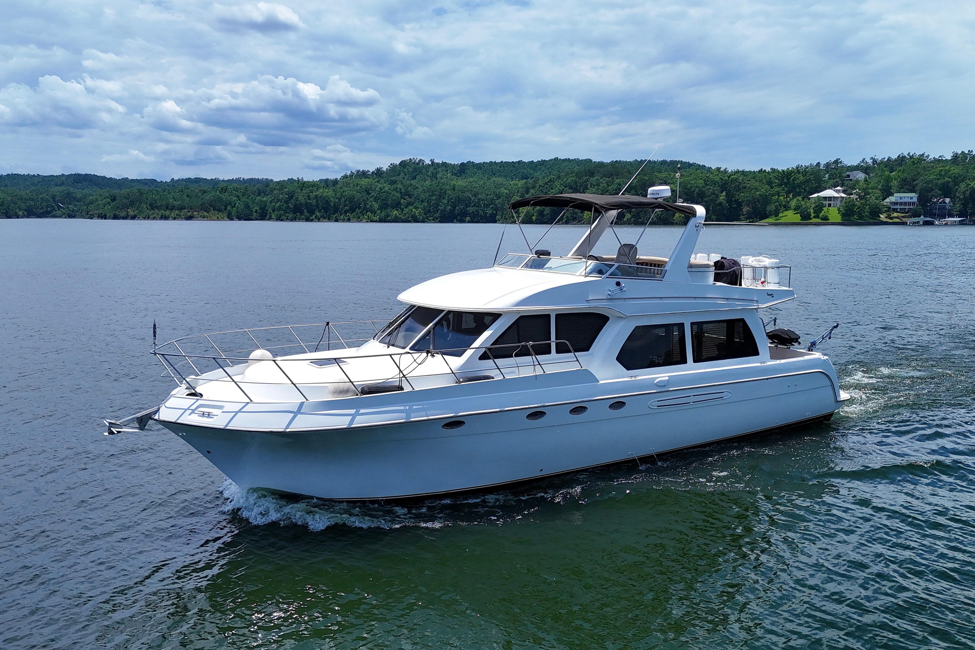 2007 Navigator 5100 yacht cruising on a serene lake under a partly cloudy sky.