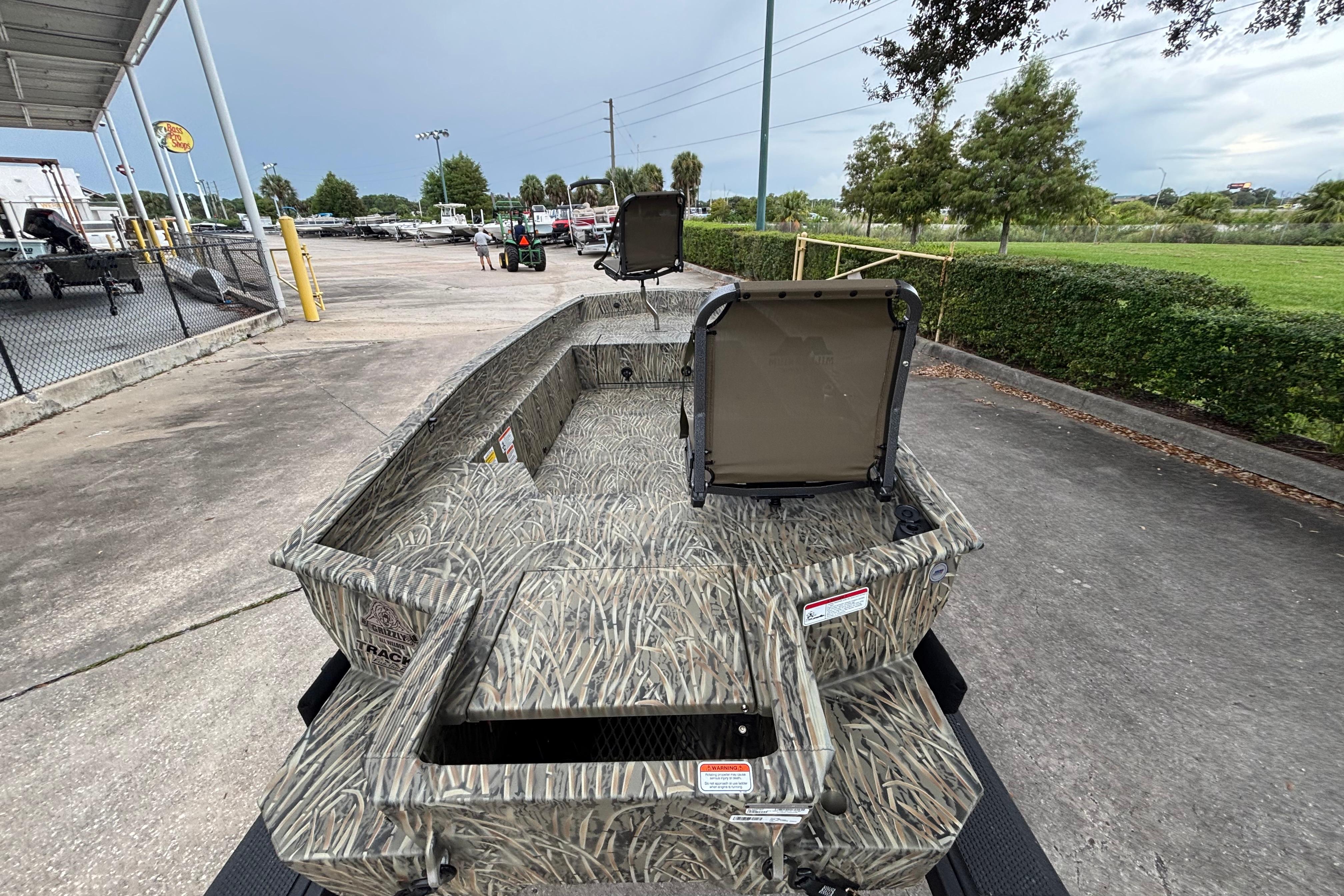 2026 Tracker Grizzly 1650 T Prairie Wings Edition boat with camouflage design, parked outdoors.