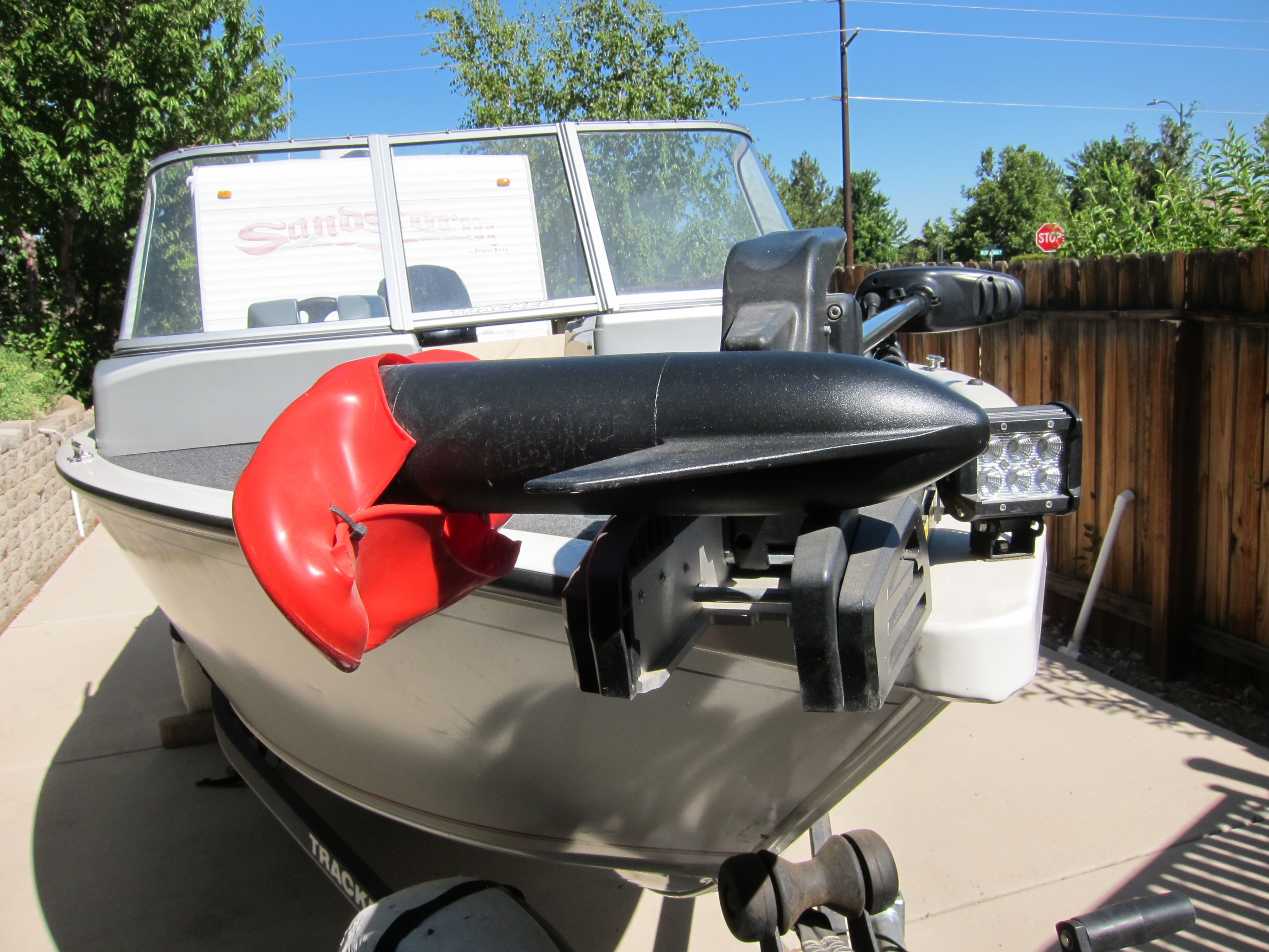 A 2018 Tracker Pro Guide V-16 WT boat on a trailer in a sunny yard.