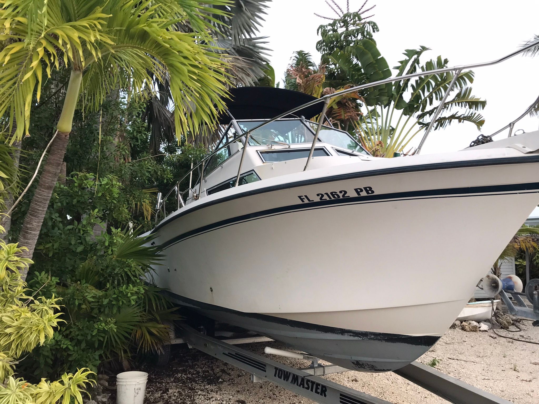 1990 Grady-White Sailfish on a trailer, surrounded by tropical plants.