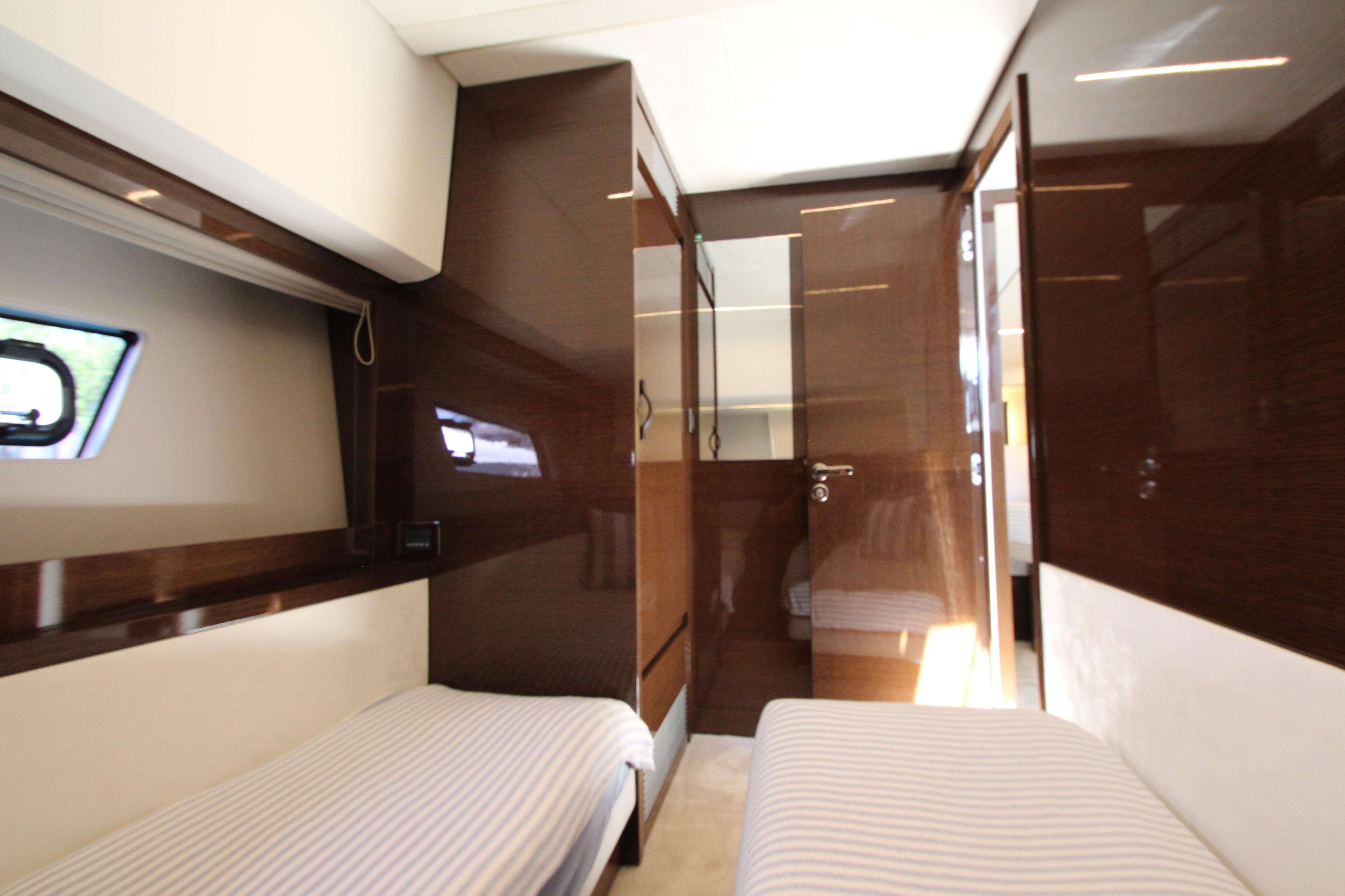 Luxurious interior of 2022 Prestige 520 yacht with twin beds and sleek wood finishes.