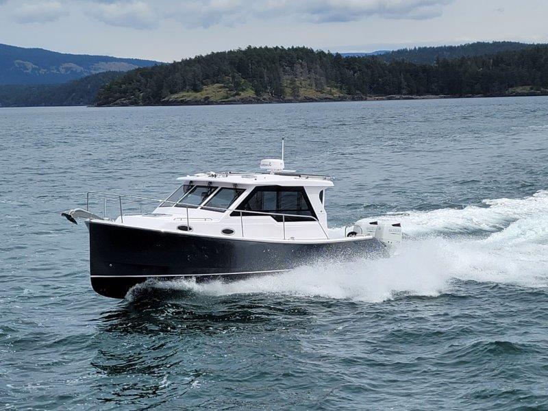 2024 True North 34 boat cruising on open water with scenic island backdrop.