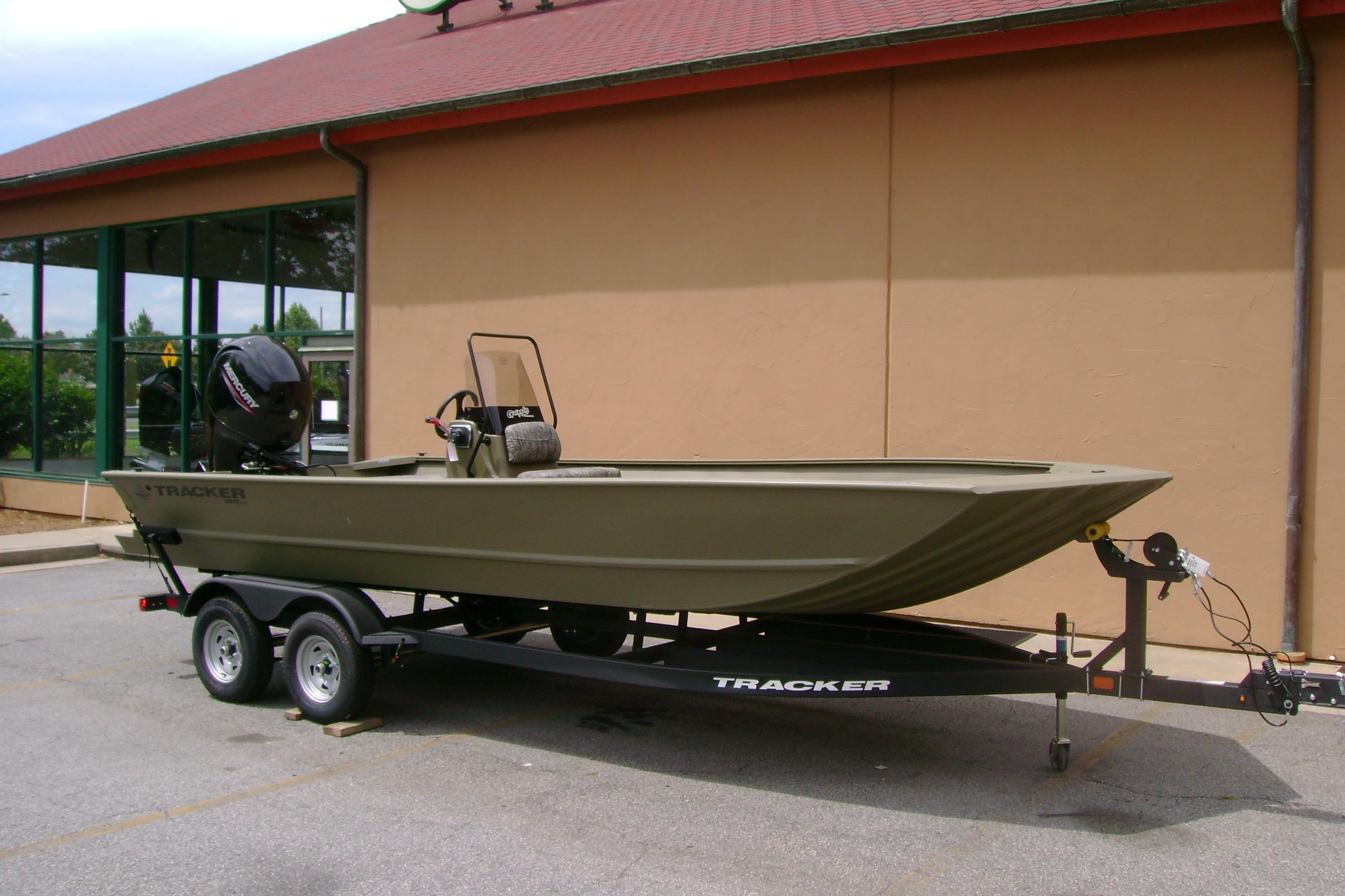 2026 Tracker Grizzly 2072 CC boat on trailer, parked outside a building.