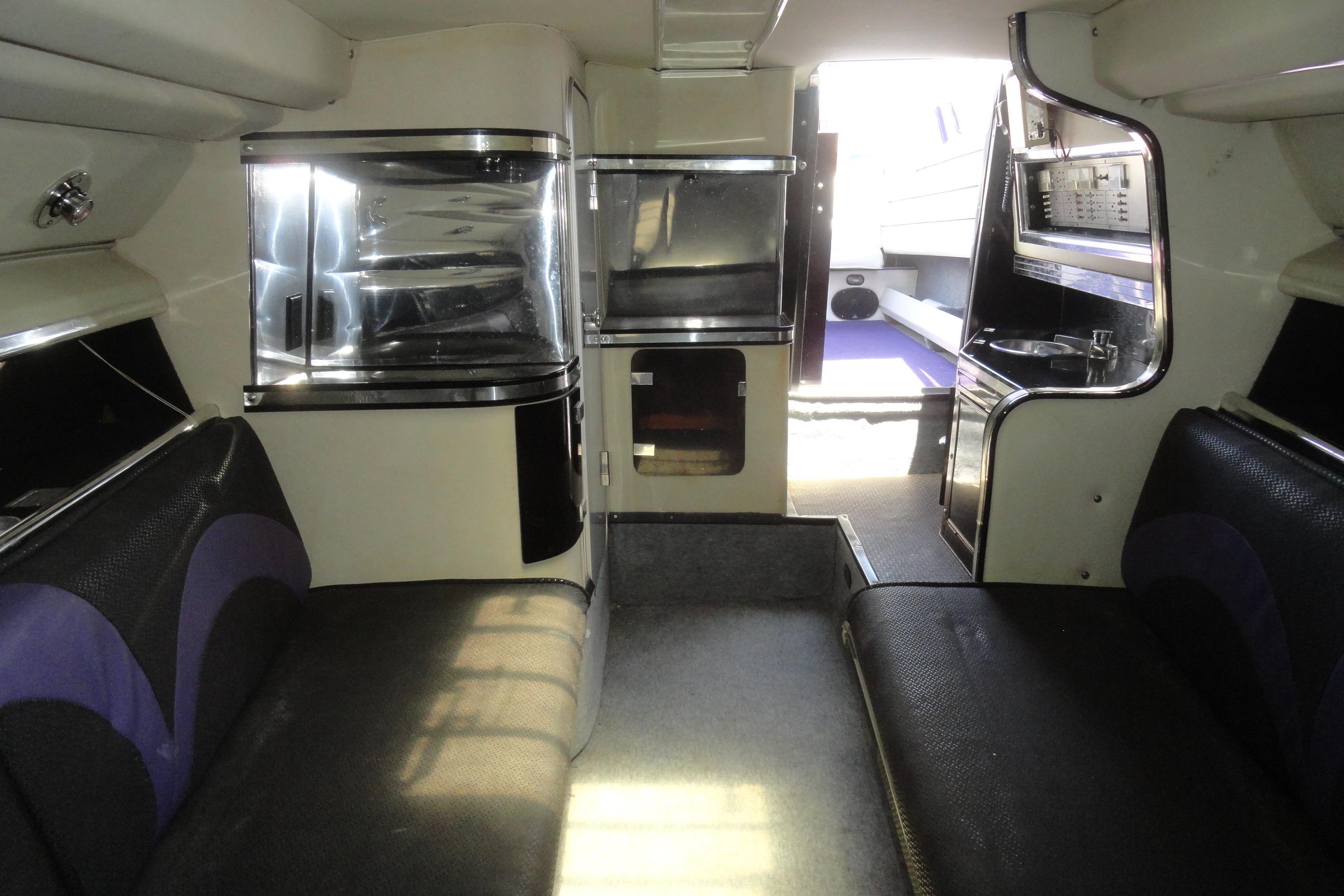 Interior of 1988 Wellcraft 34 Scarab boat, featuring seating and compact kitchenette.