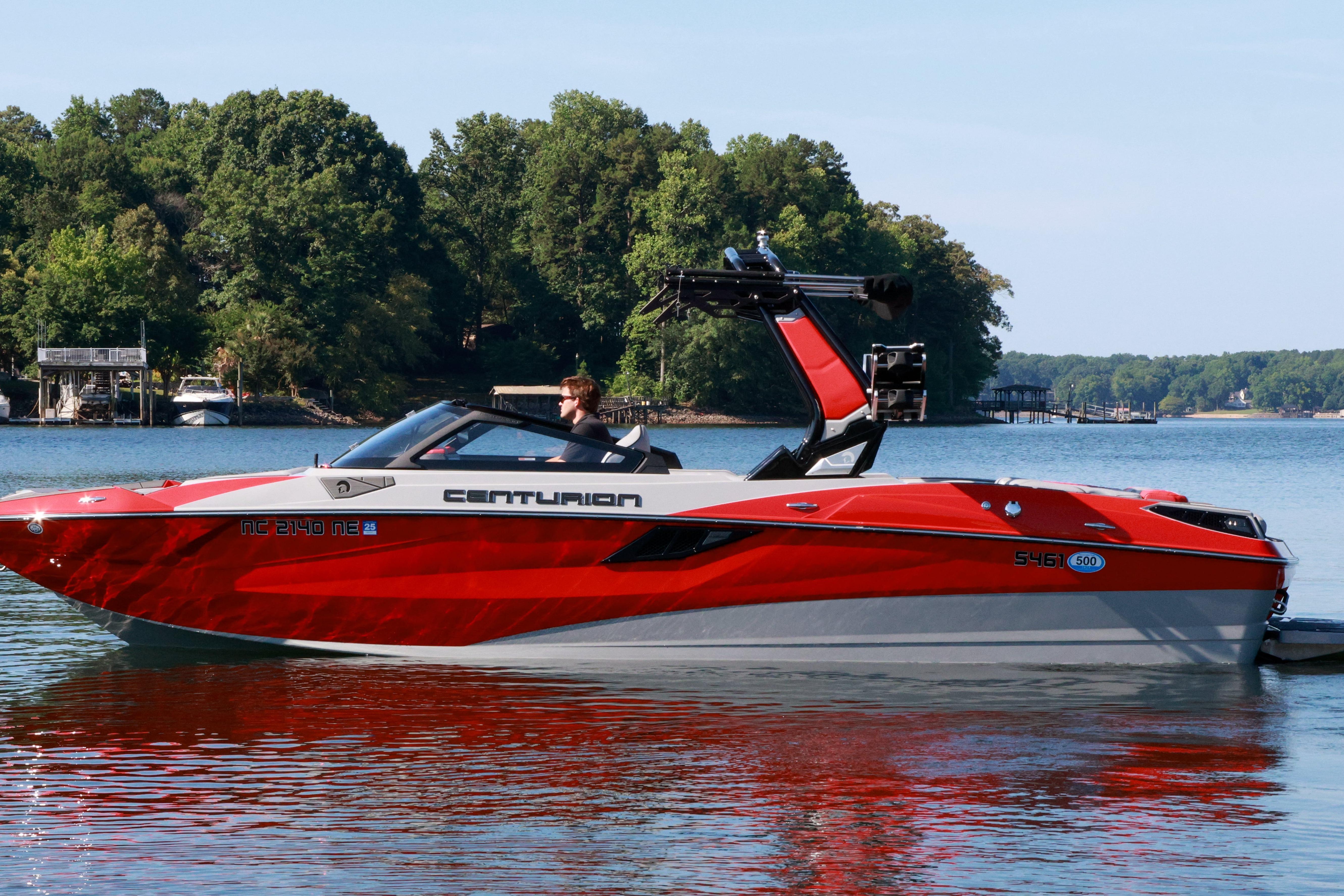 2024 Centurion Fi23 boat in vibrant red on a serene lake.