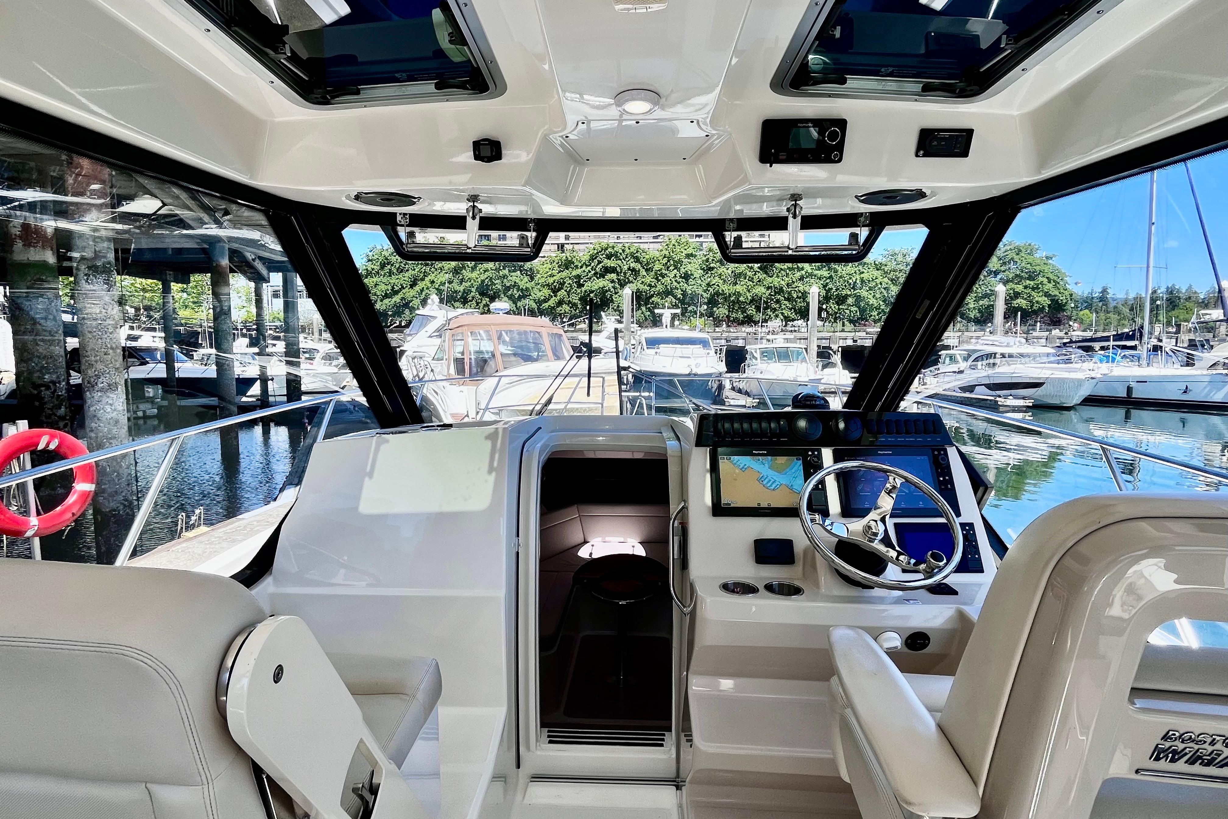 Interior view of 2026 Boston Whaler 325 Conquest Pilothouse at marina, featuring helm and navigation equipment.