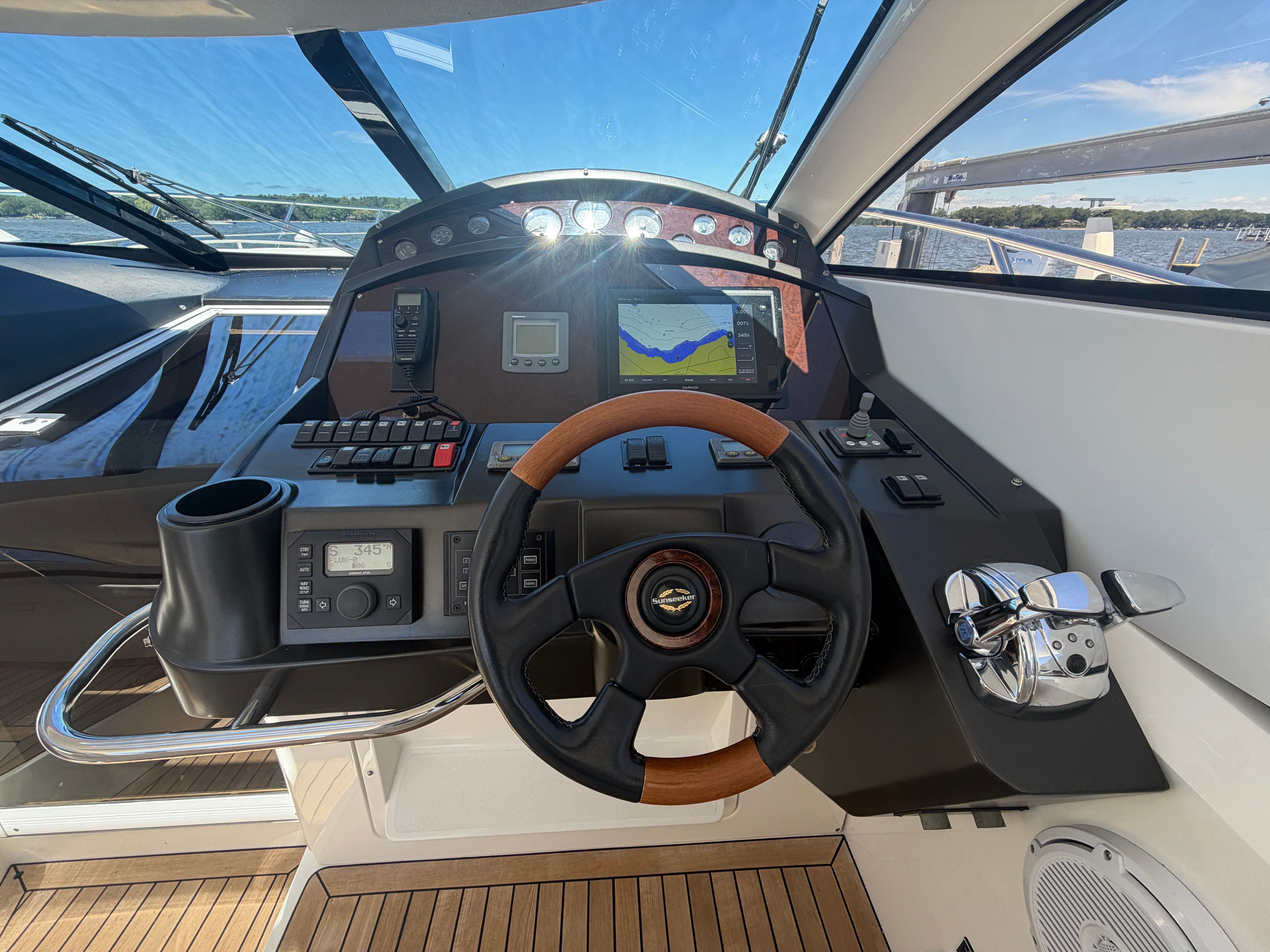 The cockpit of a Sunseeker Portofino 53 with modern instruments and a wooden steering wheel.