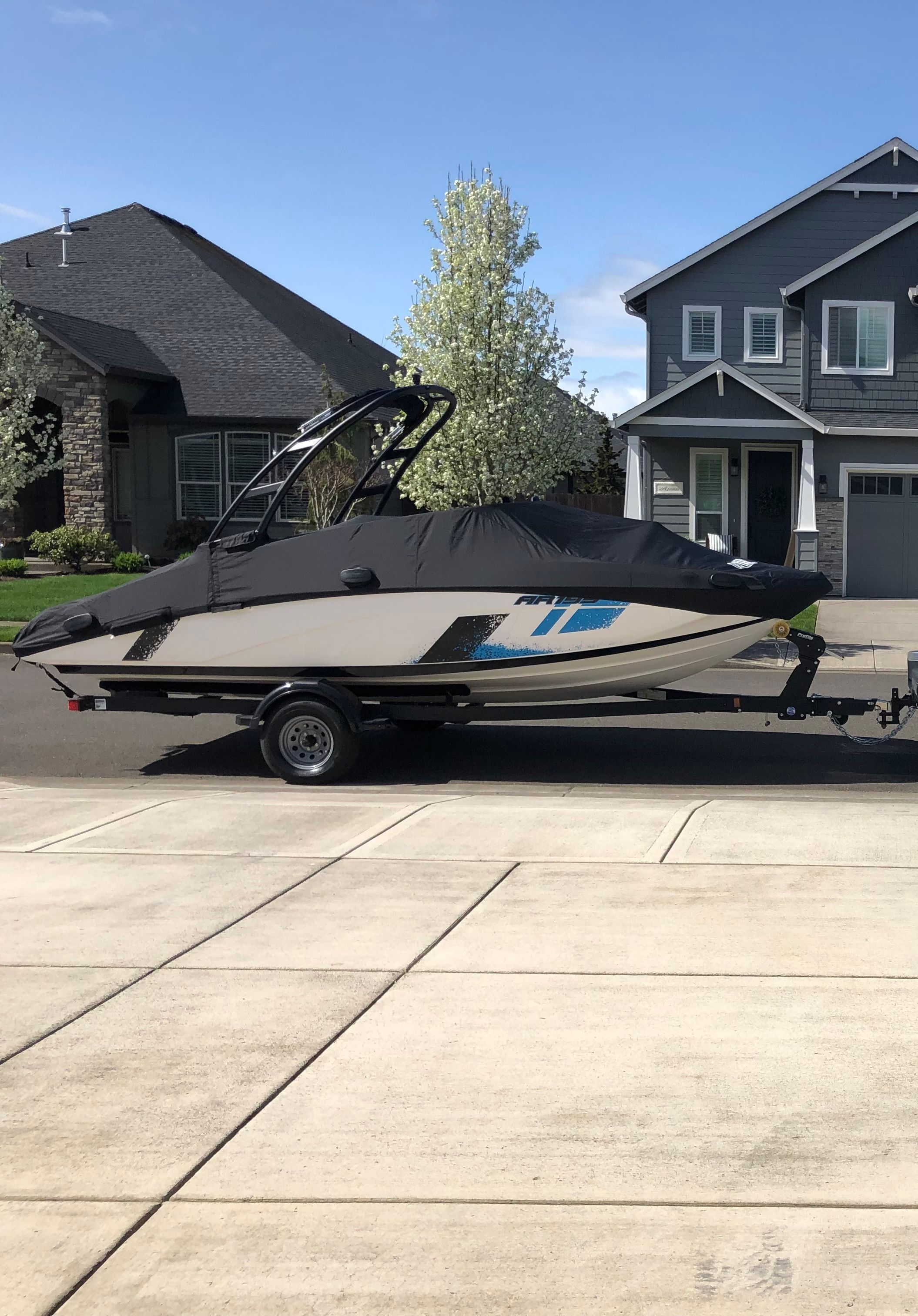 A Yamaha AR195 boat on a trailer parked in front of a house.