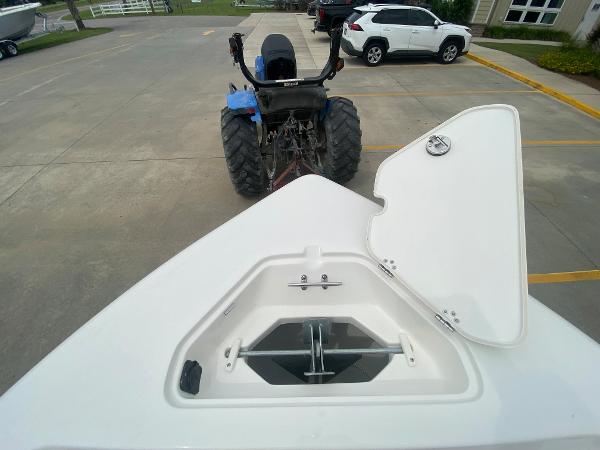 2024 Key West 189 FS boat anchor compartment with open lid, parked near a tractor and white SUV.