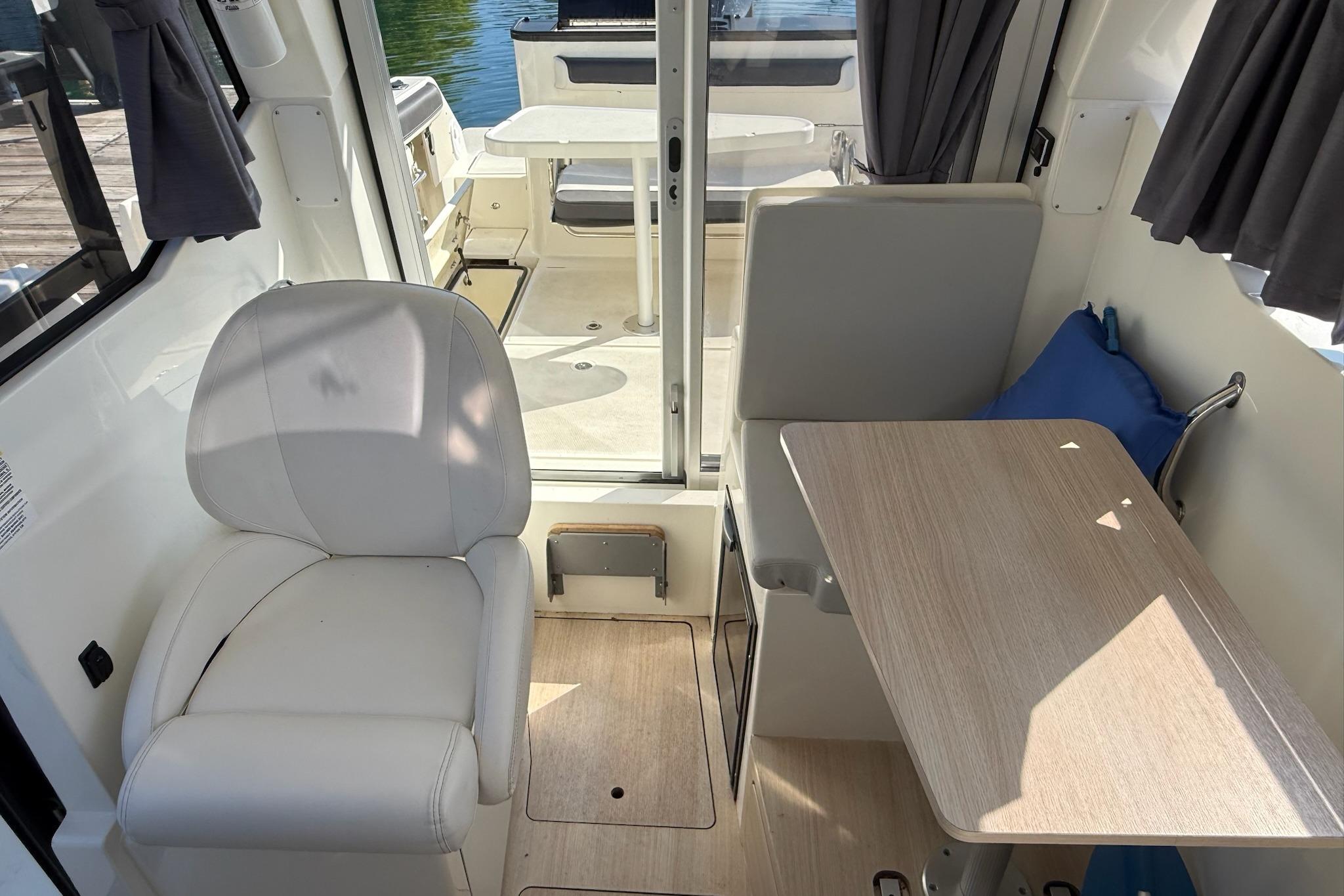 2024 Bayliner Trophy T25 Pilothouse interior with seating and table, showcasing modern design.
