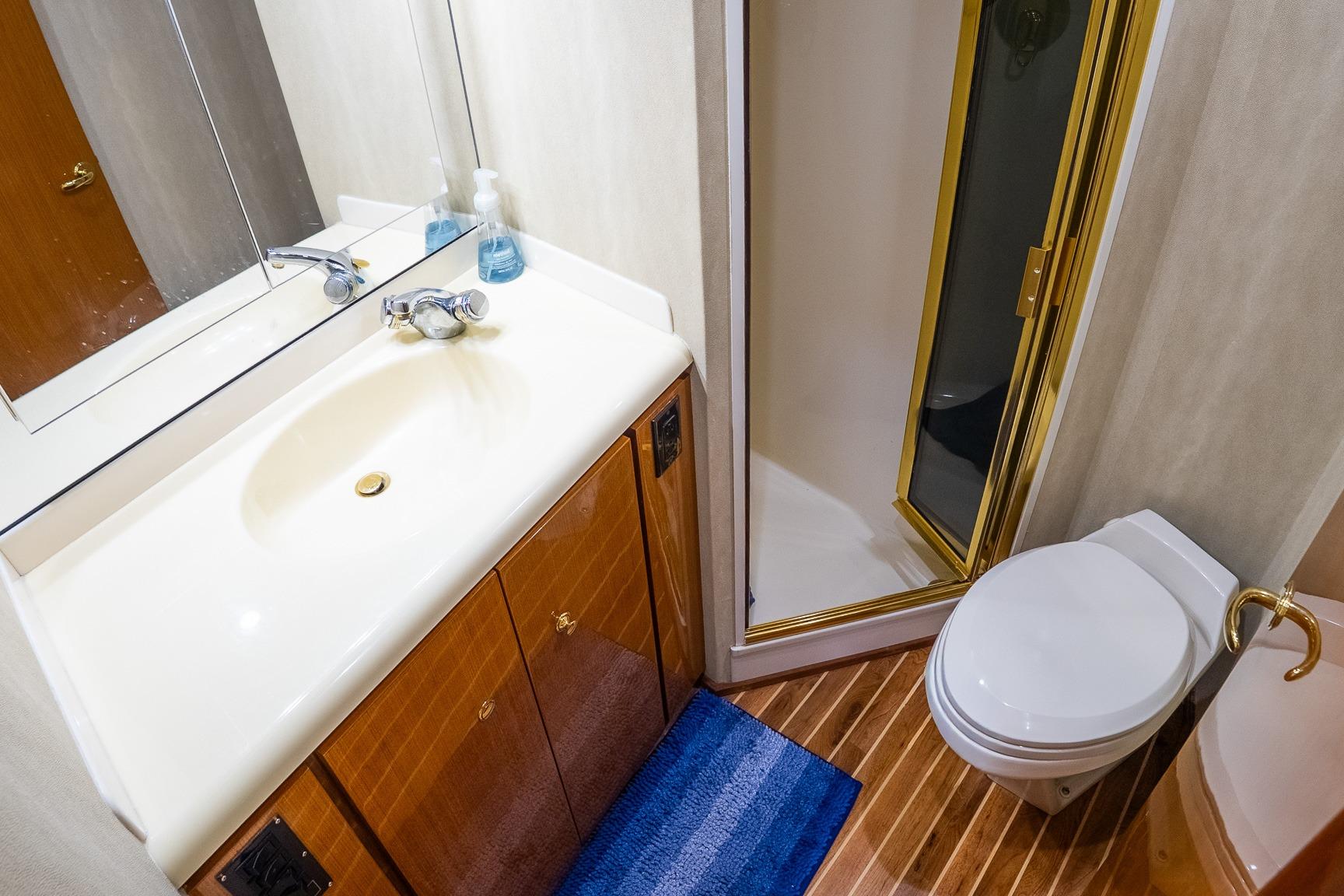 Bathroom interior of 2002 Viking 61 Enclosed Bridge yacht with shower, sink, and toilet.