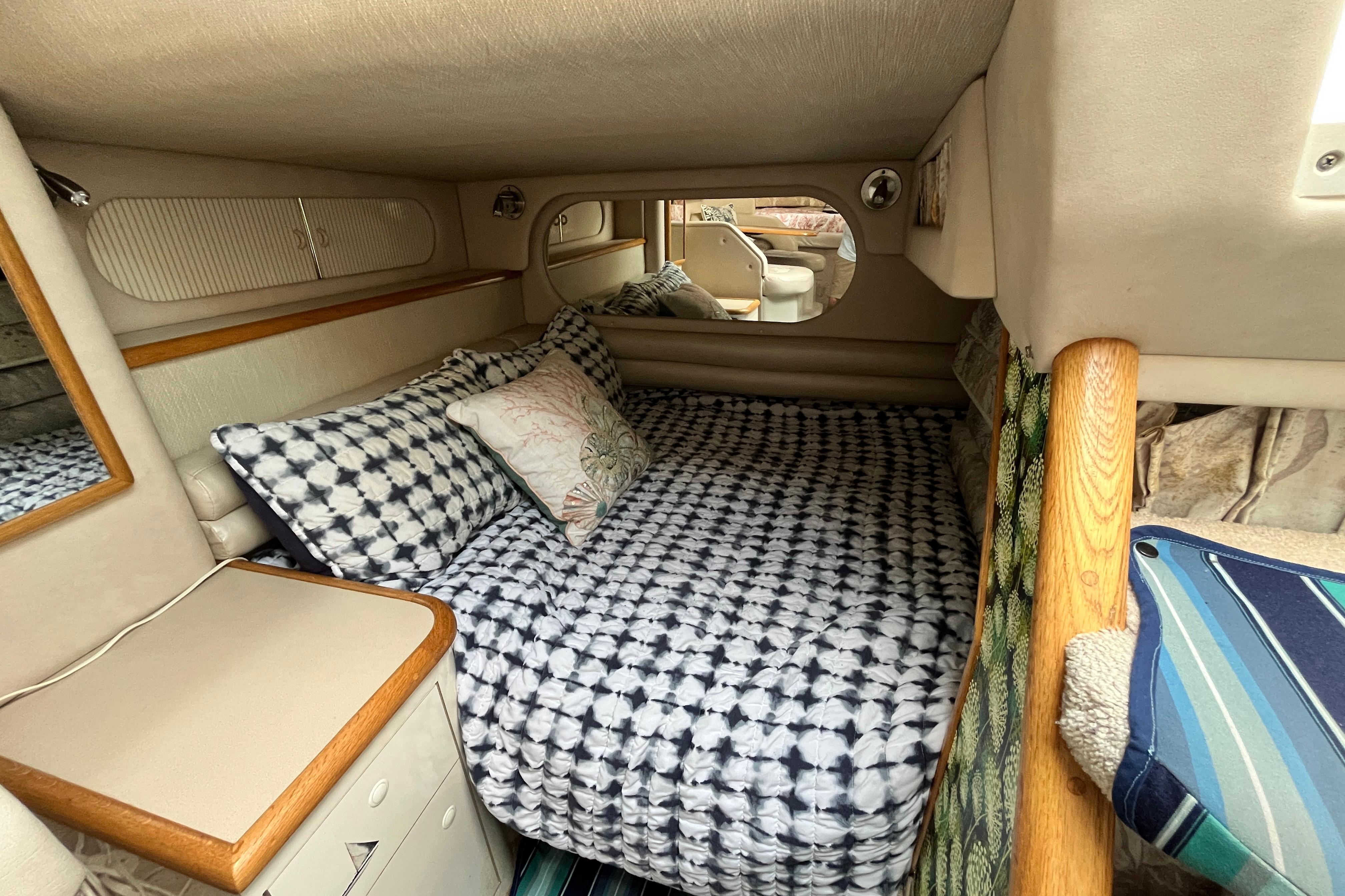 Cozy cabin interior of a 1995 Sea Ray Sundancer 330 with patterned bedding and wood accents.