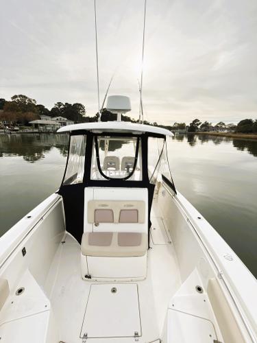 2016 Cobia 296 Center Console boat on calm water, featuring spacious deck and seating.