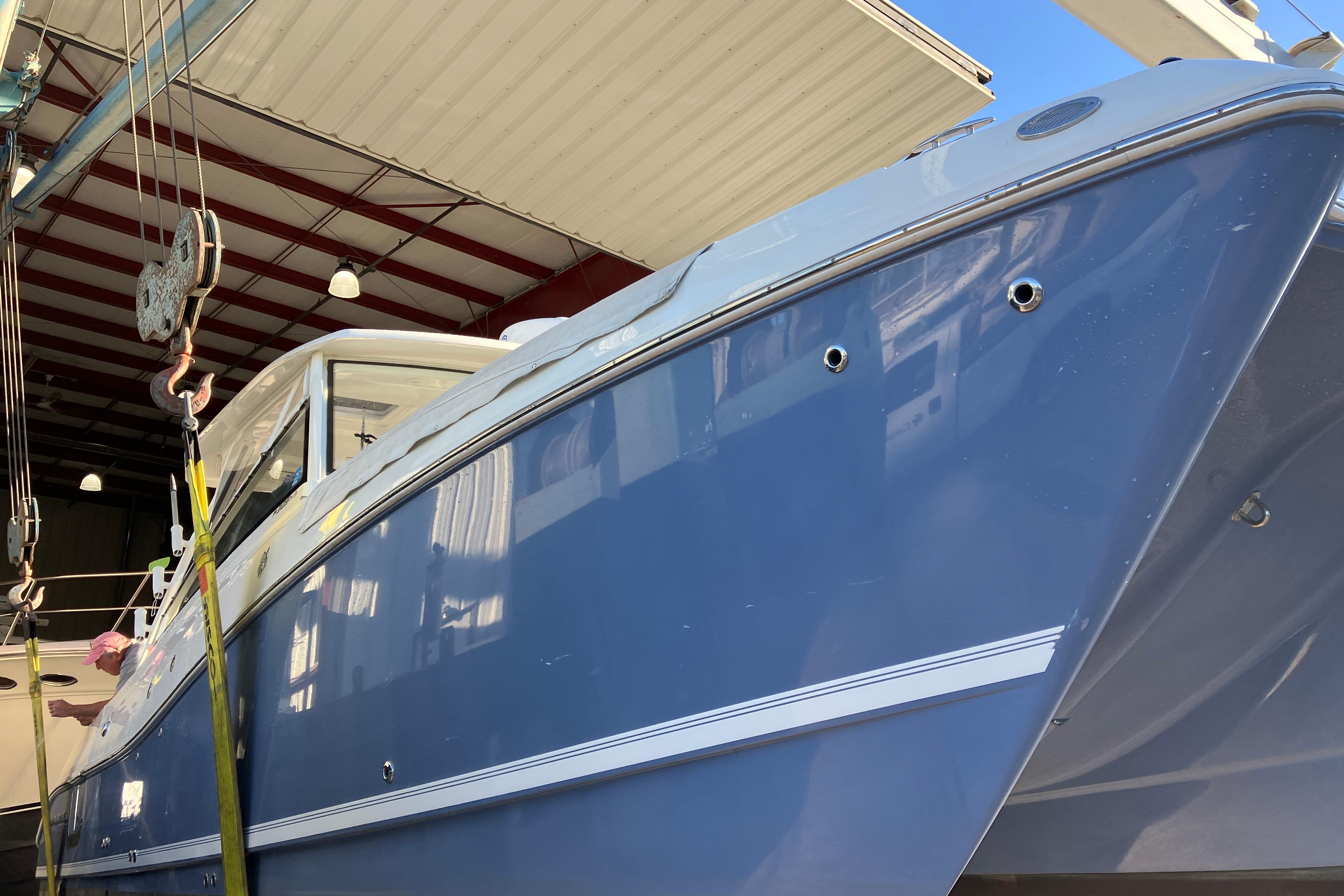 2021 World Cat 320 DC boat in a workshop, blue hull, under maintenance.