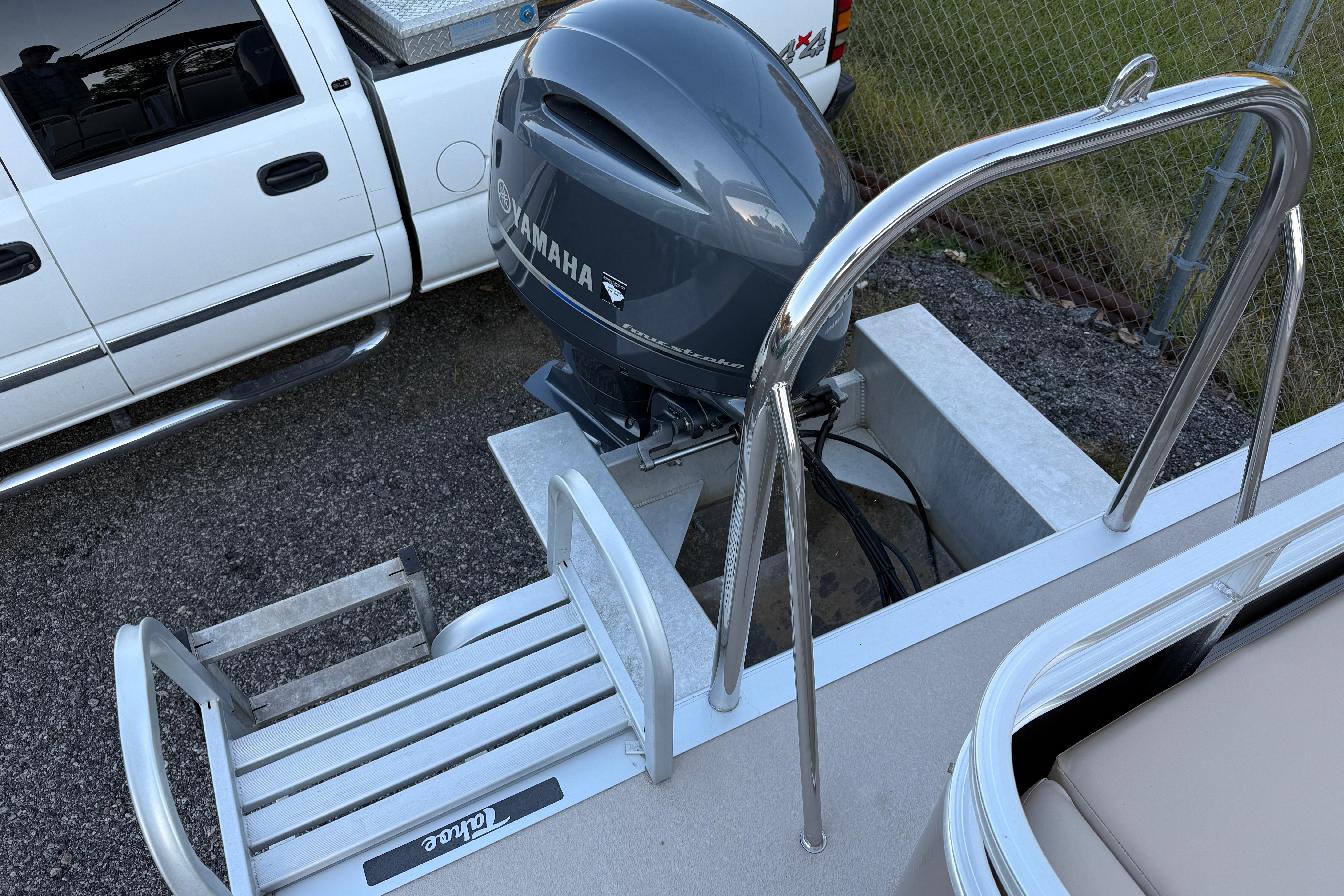 2011 Tahoe Pontoon 2485 DRL with Yamaha outboard motor and ladder, parked beside a white truck.