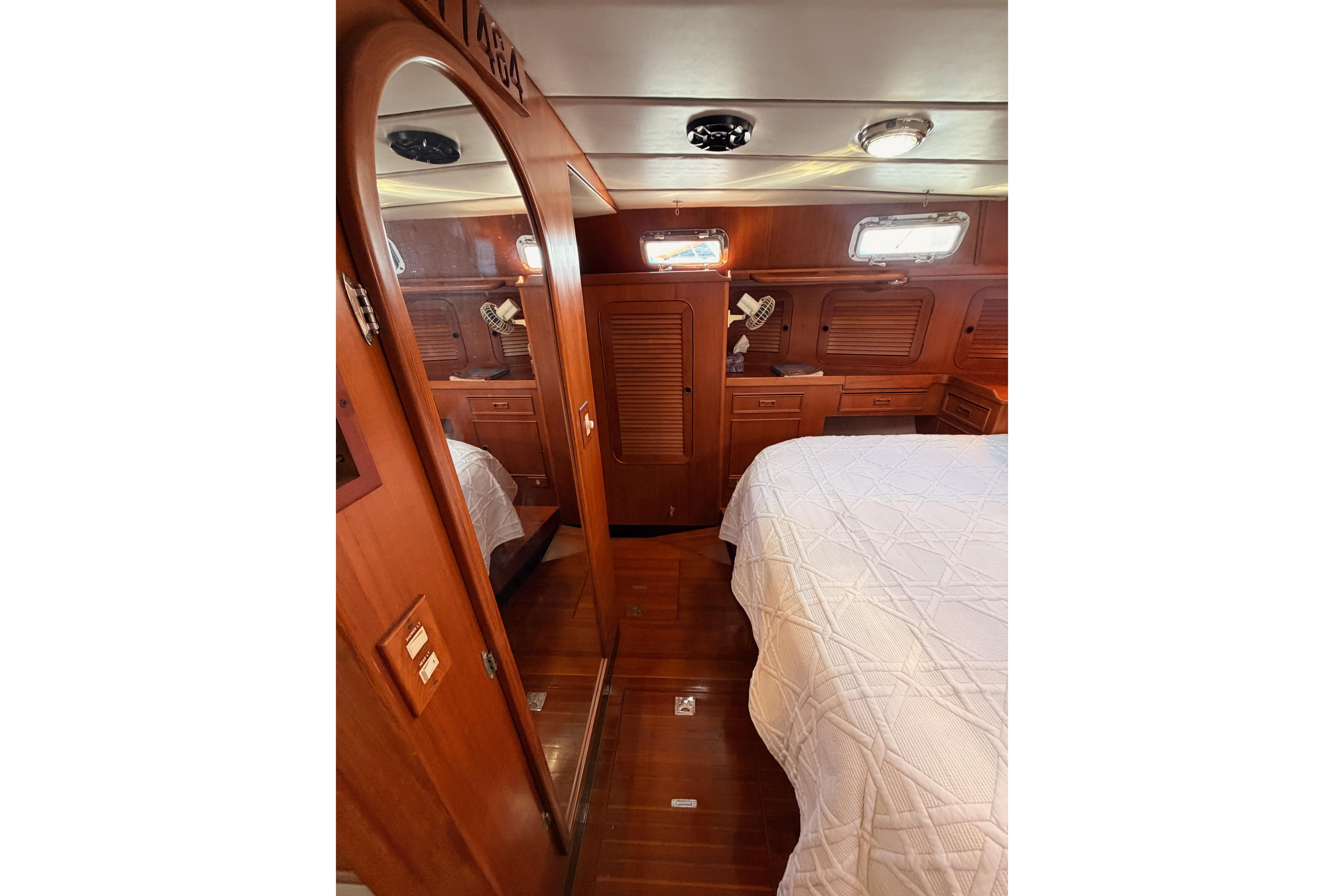 Luxurious wooden interior of a 1991 Hylas 51 yacht cabin with bed and storage.