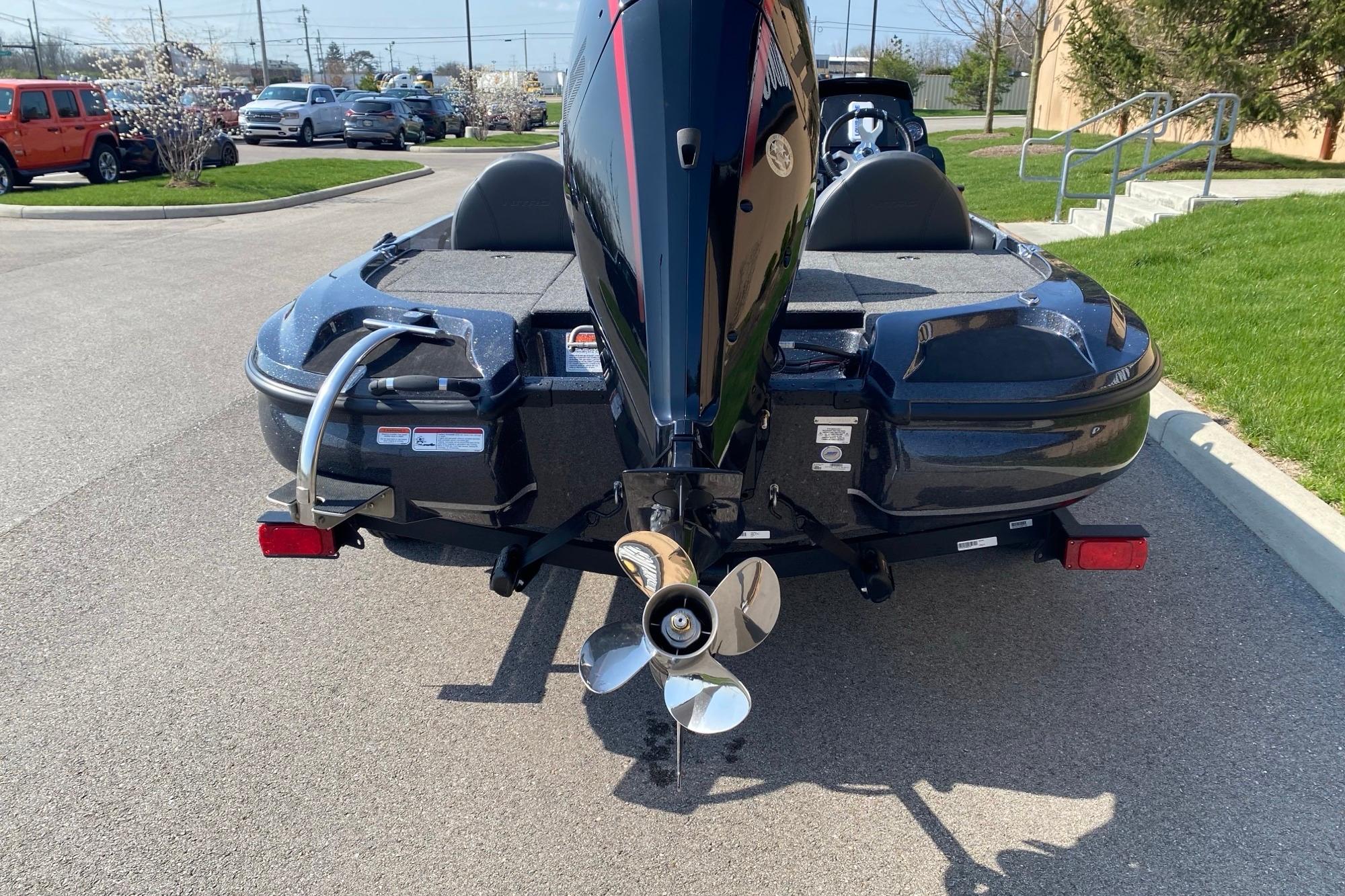 Rear view of a 2026 Nitro Z17 boat with an outboard motor in a parking lot.