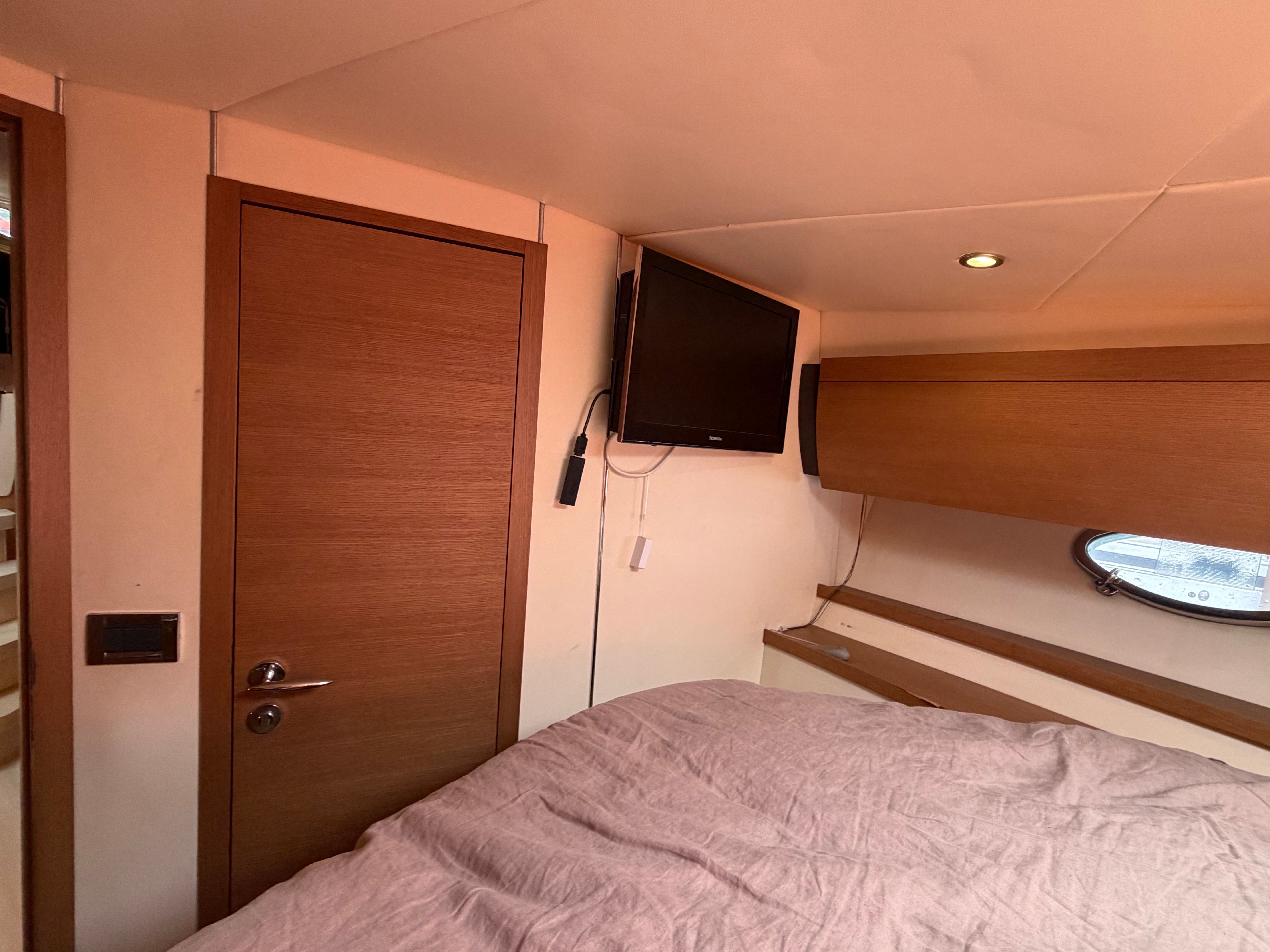 Interior of a 2011 Azimut Atlantis 40 with bed, wooden door, and TV.