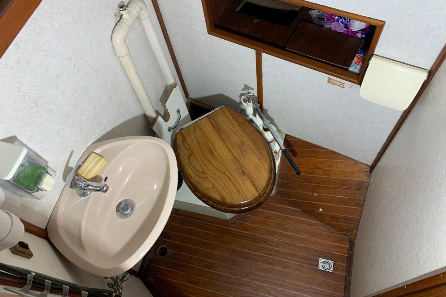 1979 Bueltjer Motorsailer bathroom with wooden toilet seat and compact sink.