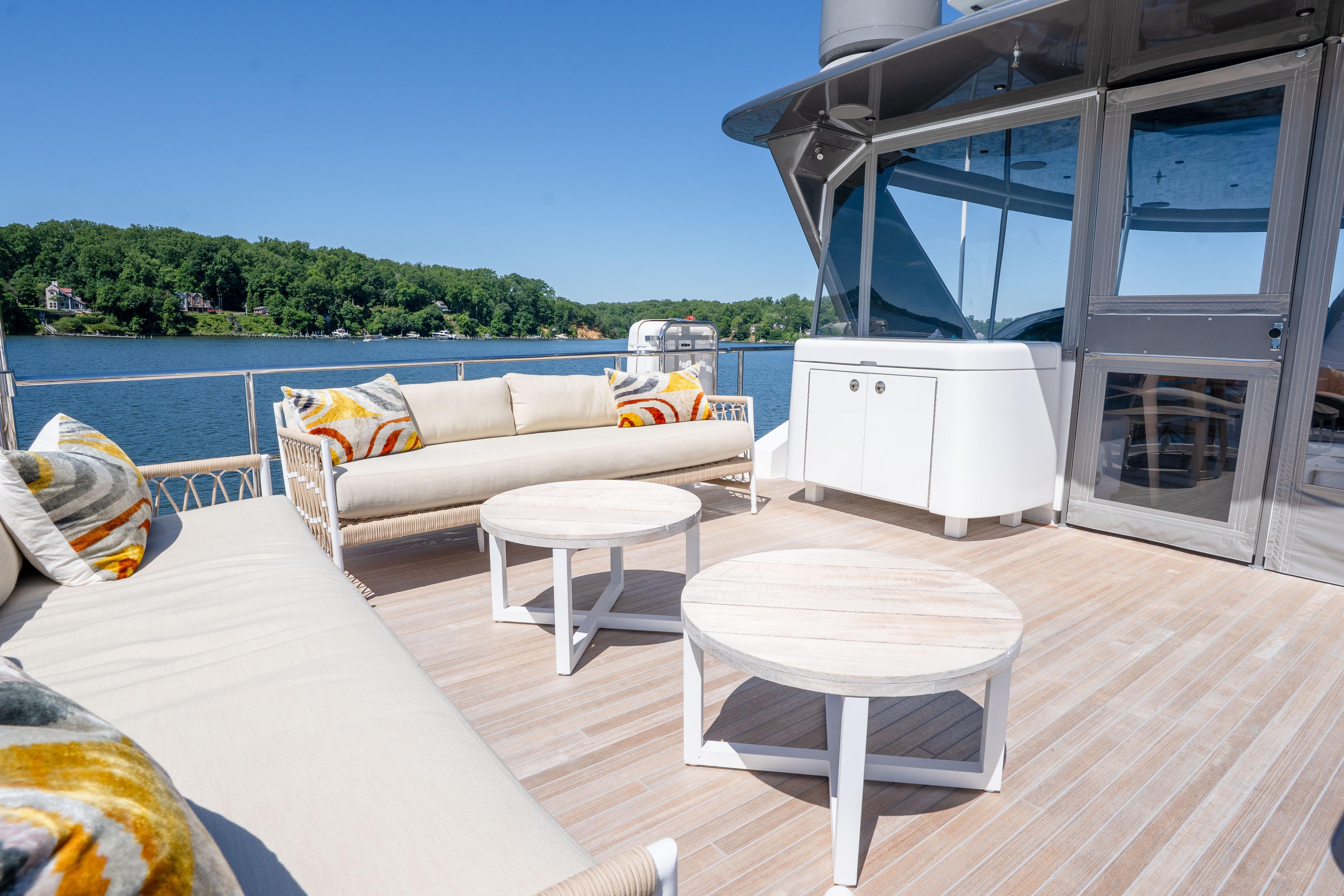 Luxurious deck of 2021 Hatteras M75 Panacera yacht with stylish seating and scenic water view.