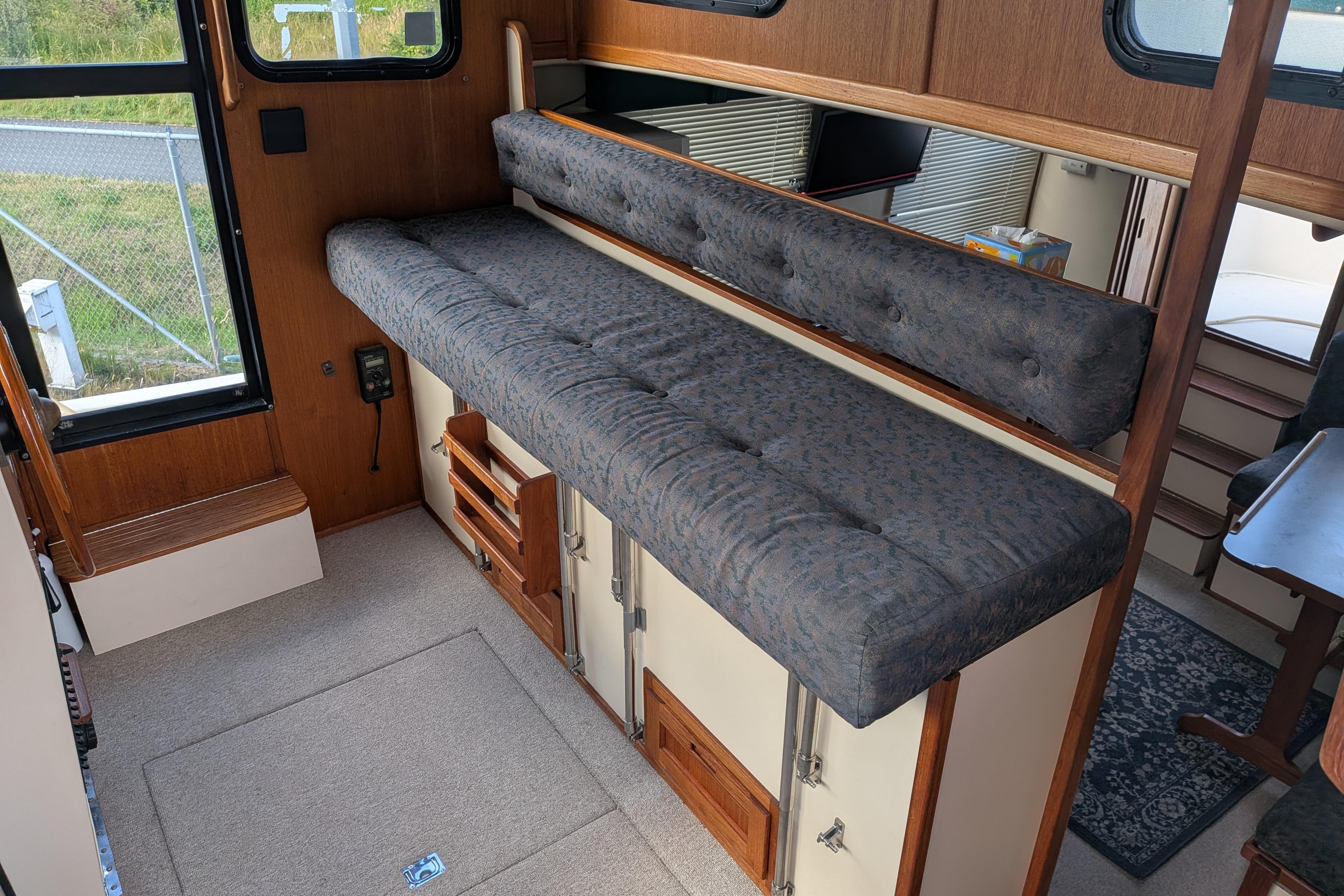 Interior of a 1998 Nordic Tug 32, featuring a cushioned bench and wooden cabinetry.