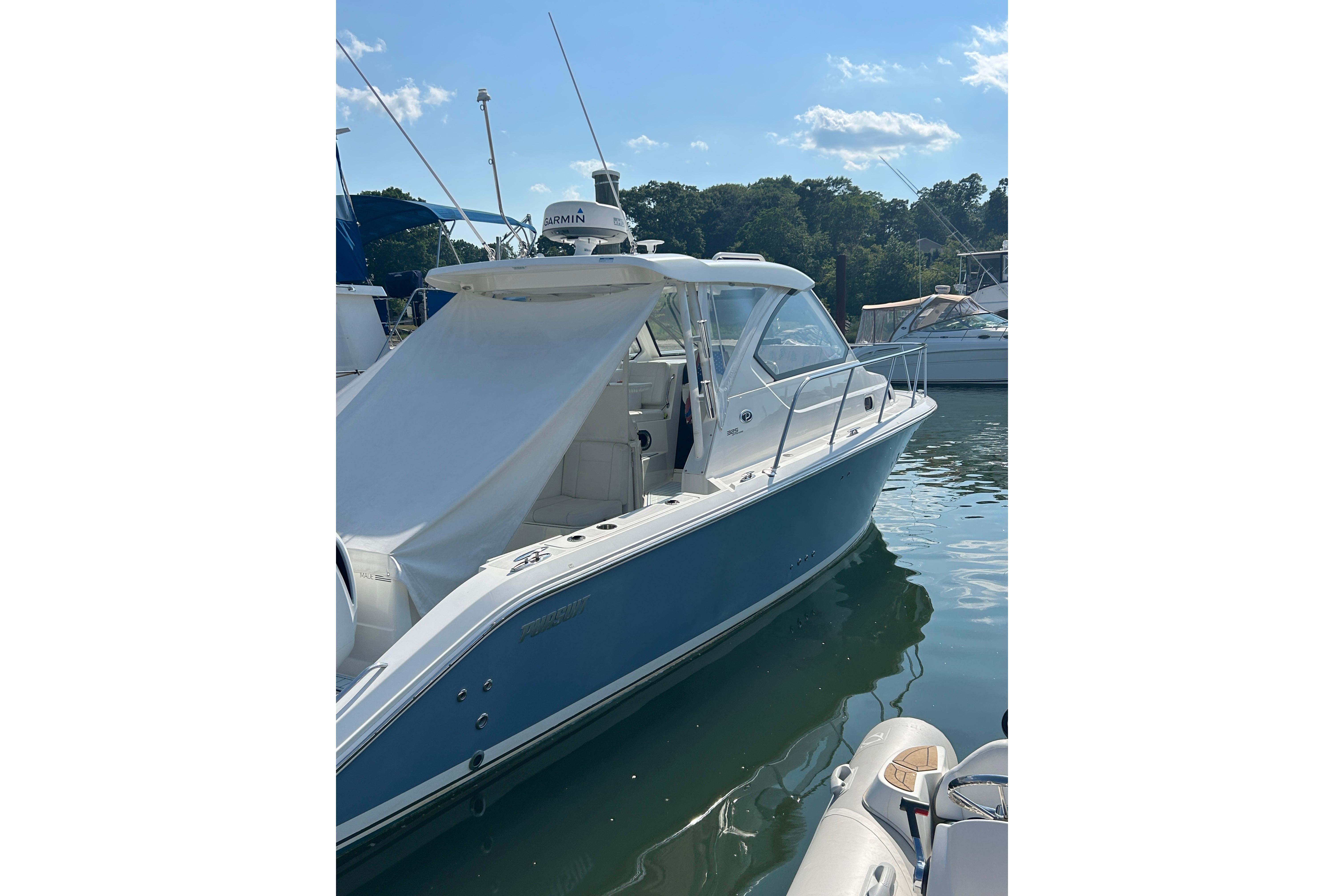 2021 Pursuit OS 325 Offshore boat docked in sunny marina.