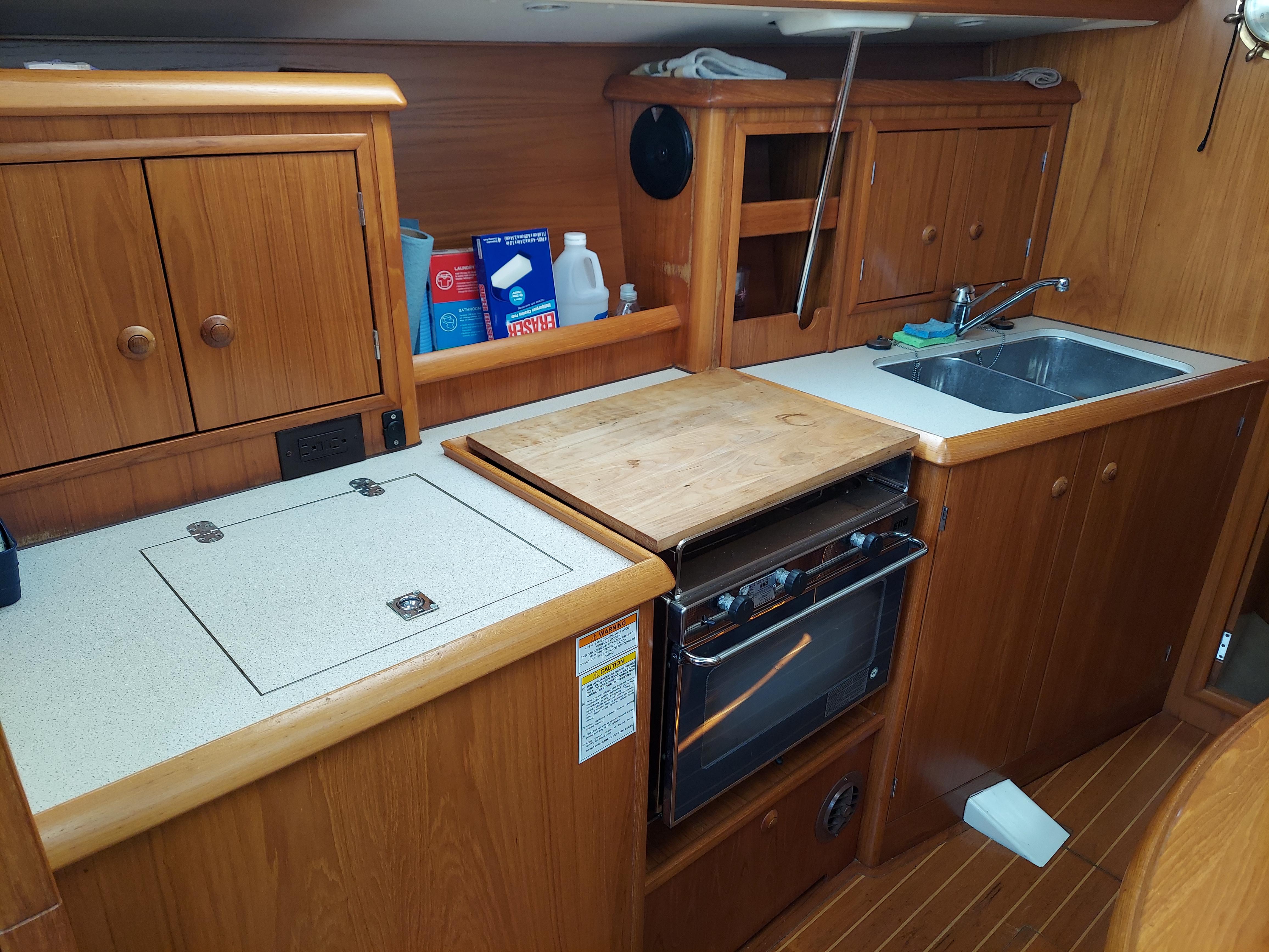 Galley kitchen in 2000 Jeanneau 34.2 sailboat with wood cabinetry and appliances.