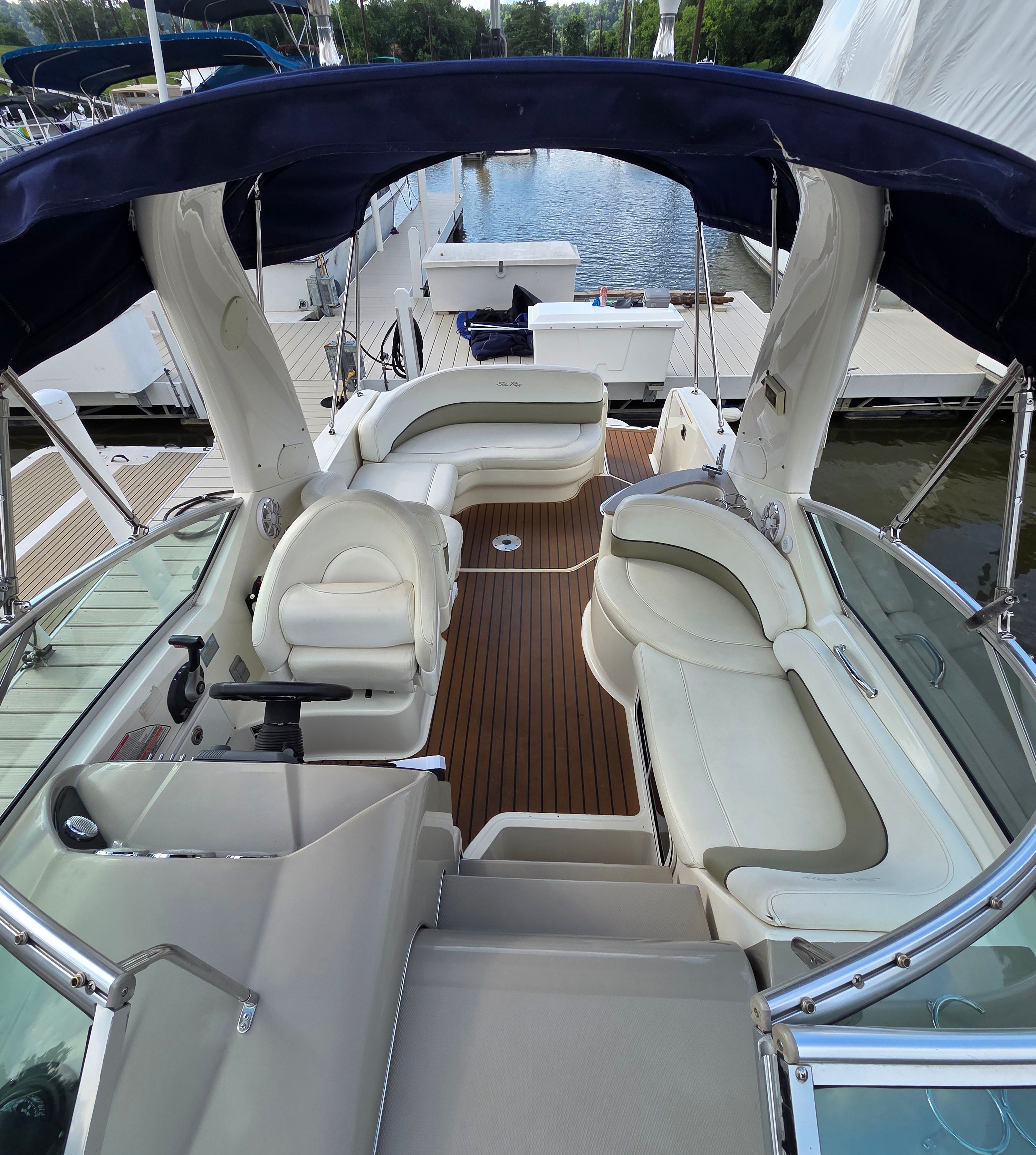 The image shows the cockpit of a 2005 Sea Ray Sundancer 260 with white seating and wood flooring.