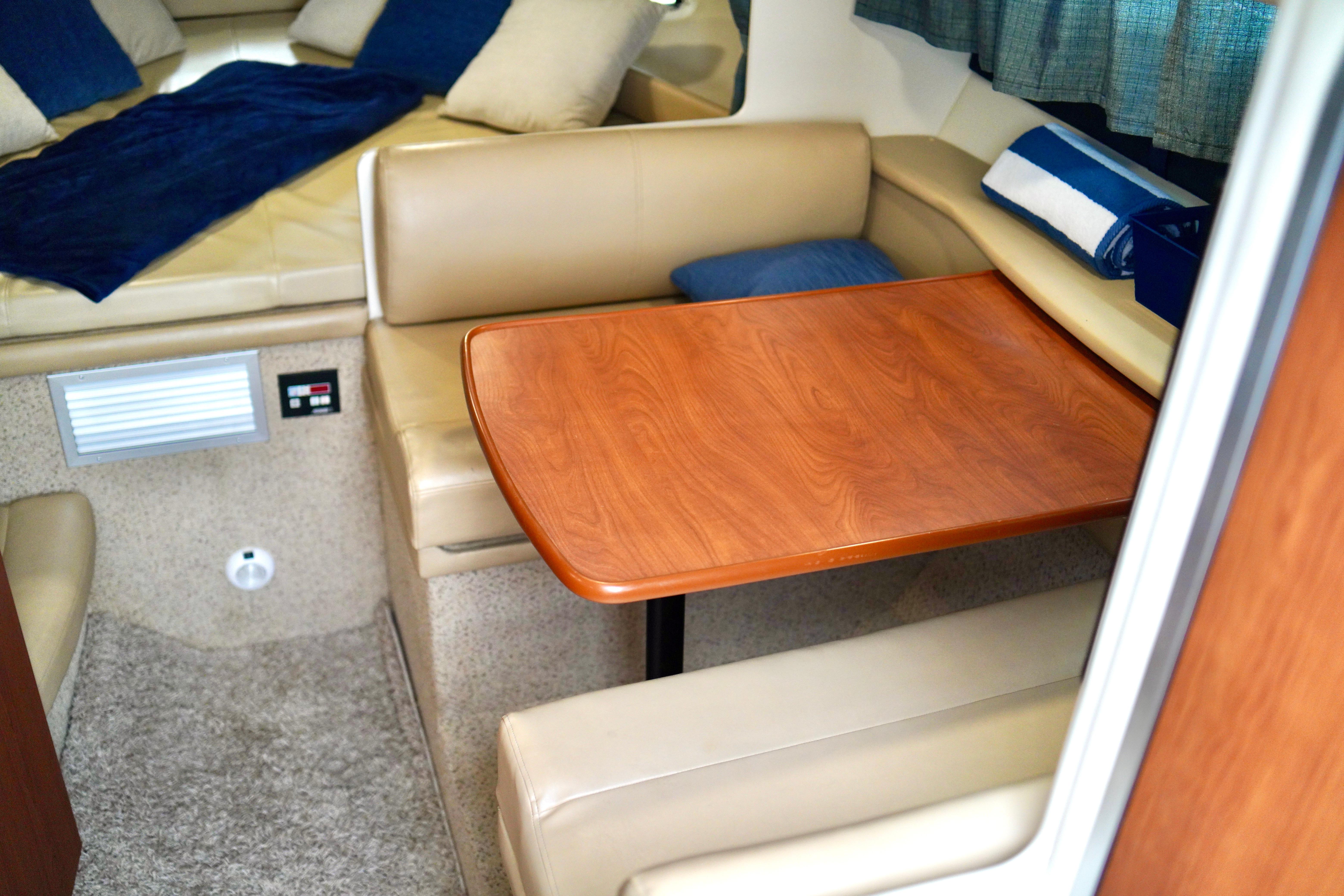 Interior of 2006 Bayliner 285 boat with cozy seating and wooden table.
