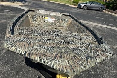 2026 Tracker Grizzly 1648 Utility boat with camouflage design in a parking lot.