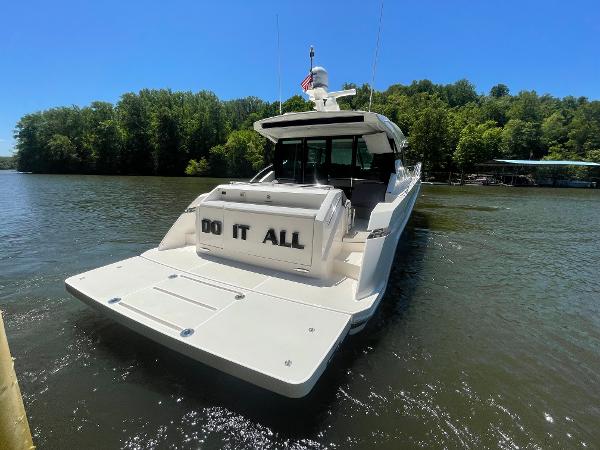 2019 Tiara Yachts C53 on a serene lake with lush green trees.