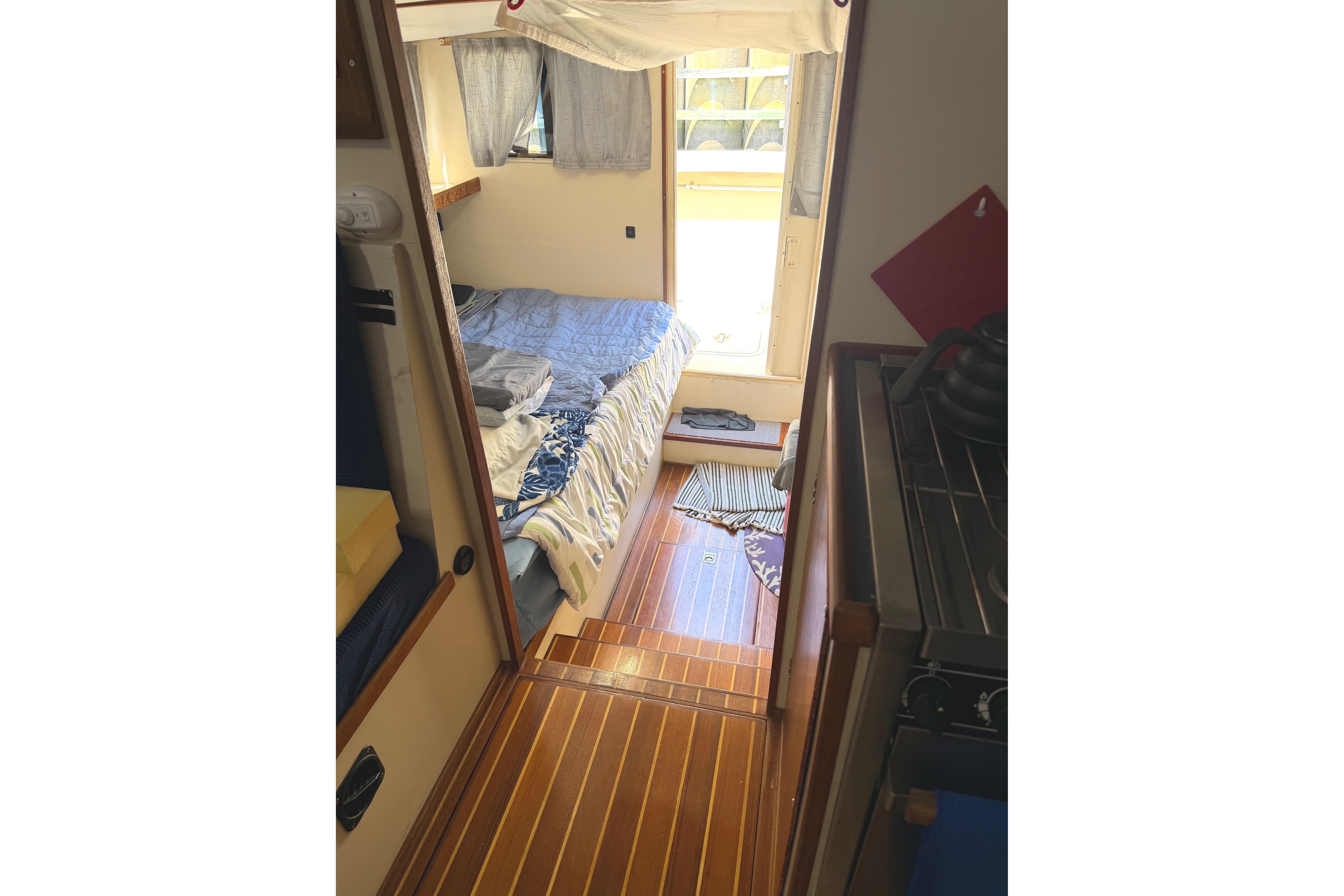 Cozy interior of a 1997 Rosborough Trawler with wooden flooring and a comfortable bed.