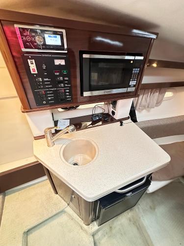 Compact kitchenette in 2015 Sea Ray 260 Sundancer with sink, microwave, and control panel.