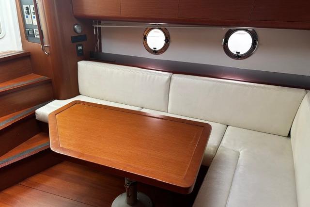 Interior of 2013 Beneteau Gran Turismo 38 yacht with white seating and wooden table.