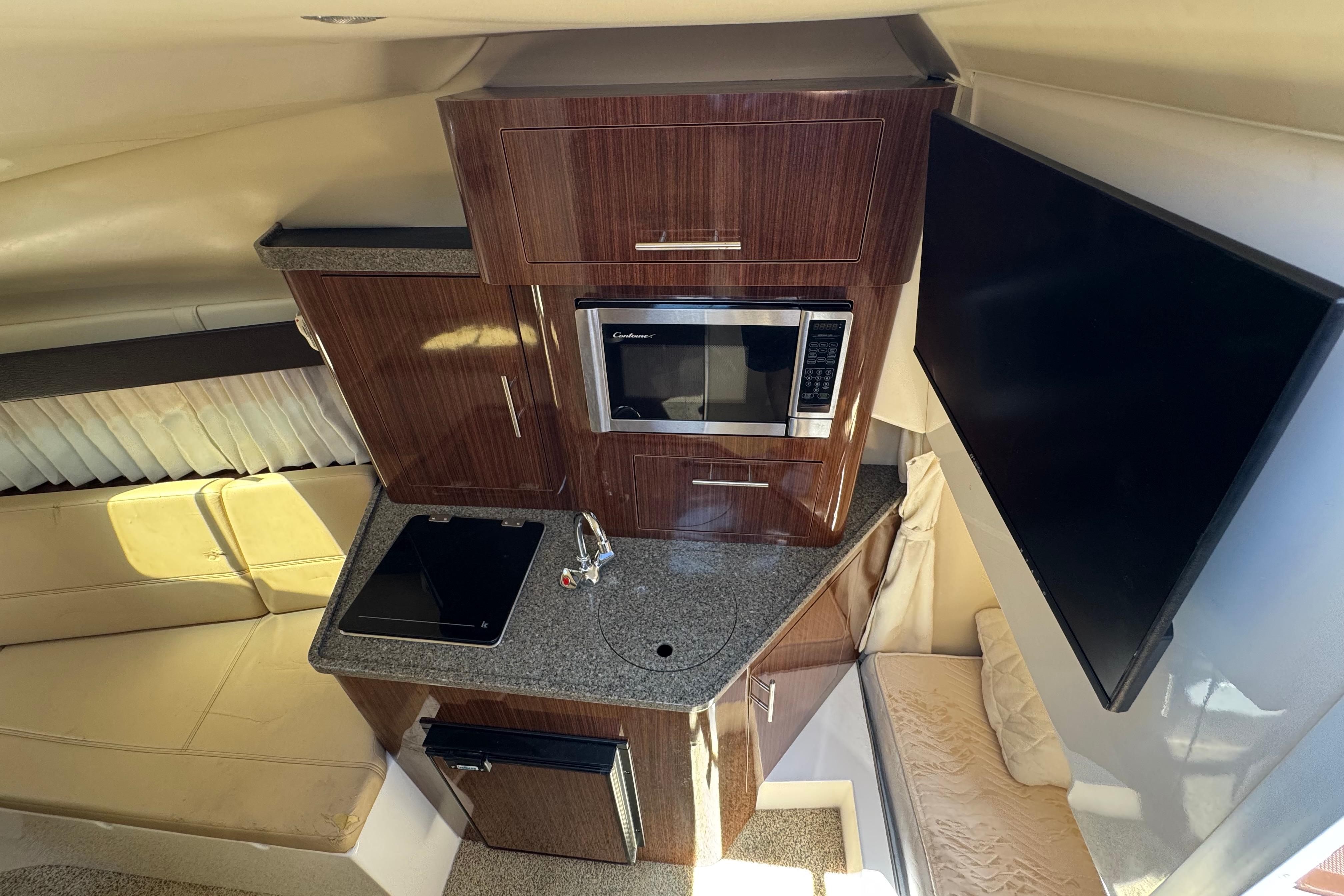 Interior of 2013 Regal 28 Express boat featuring kitchen area with microwave and TV.