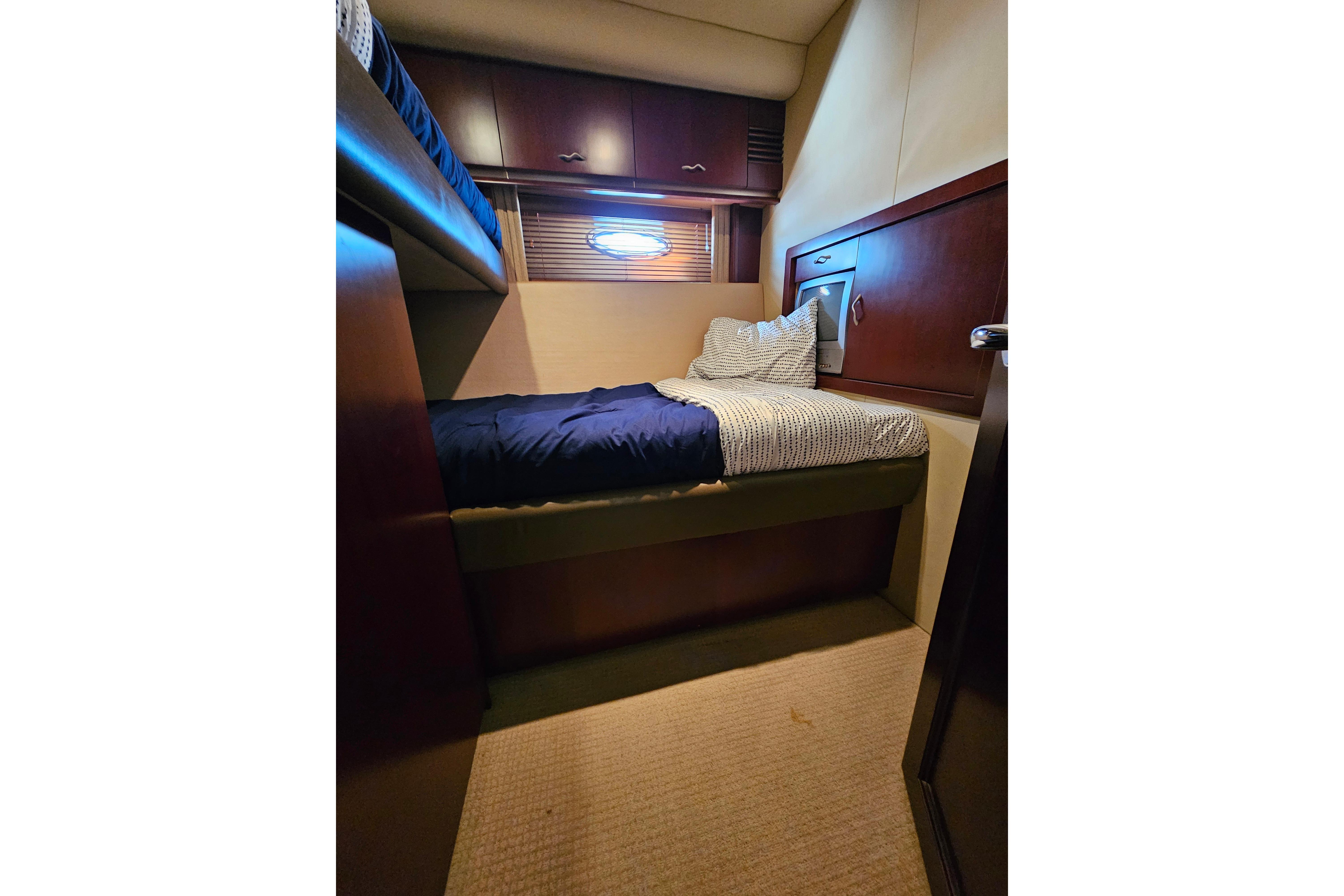 Cozy cabin interior of 2006 Sea Ray 580 Sedan Bridge yacht with bed and porthole.