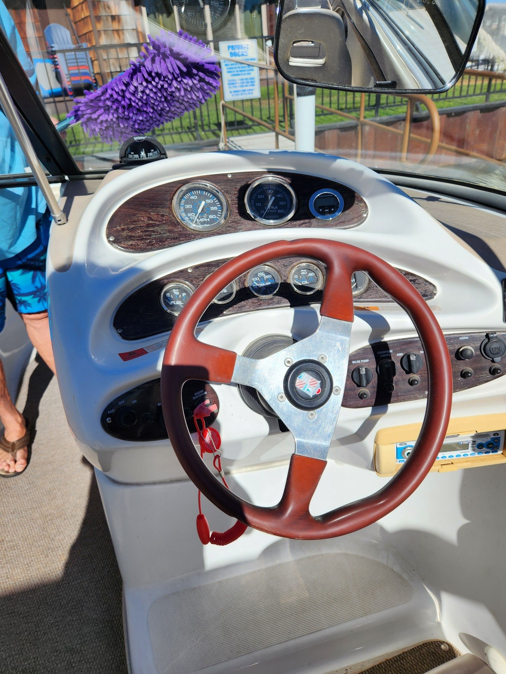 The cockpit of a Chris-Craft 240 Bowrider with a wooden steering wheel and instruments.
