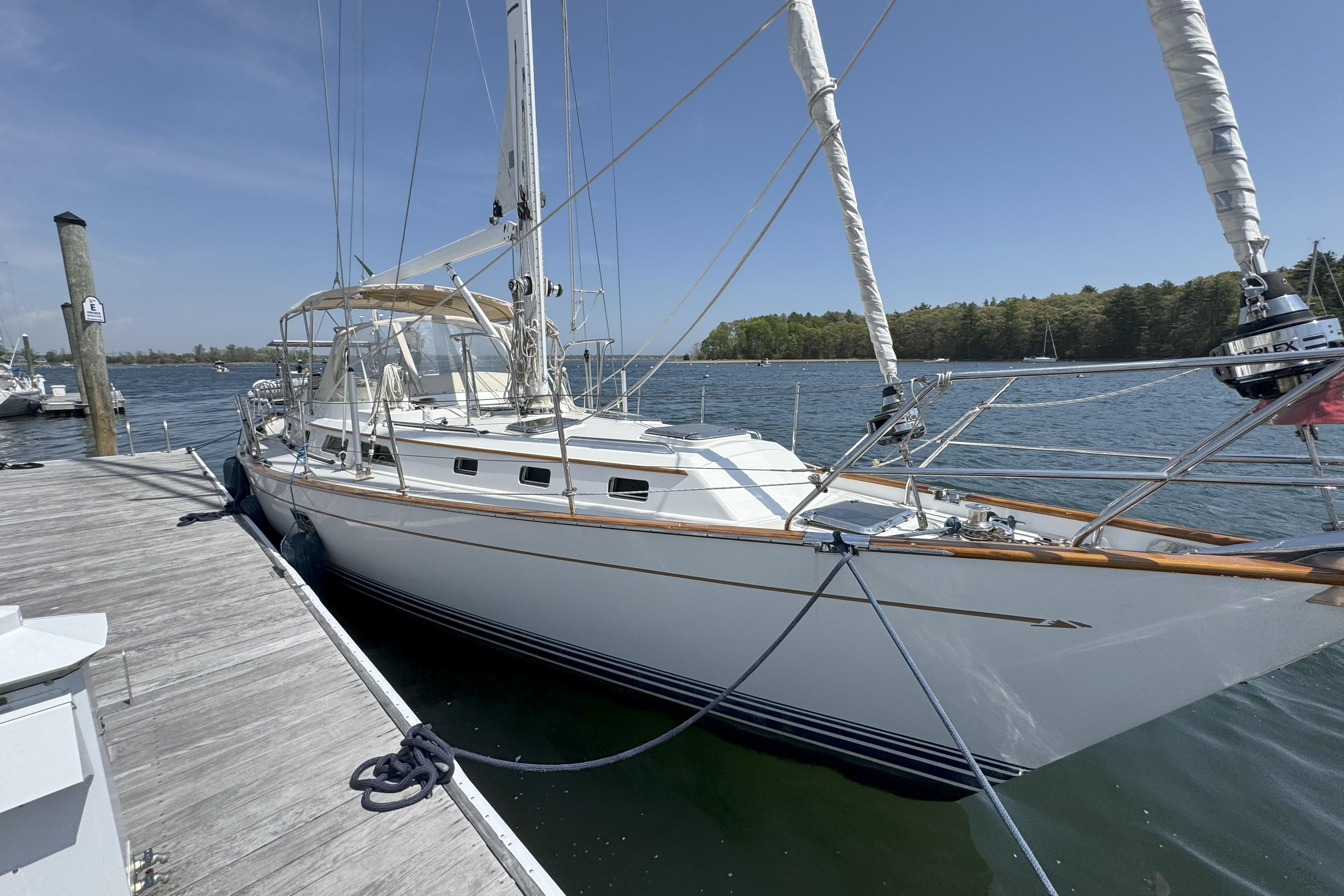 Sailboat docked at marina, 2013 Passport 470 Center Cockpit, clear sky, calm water.